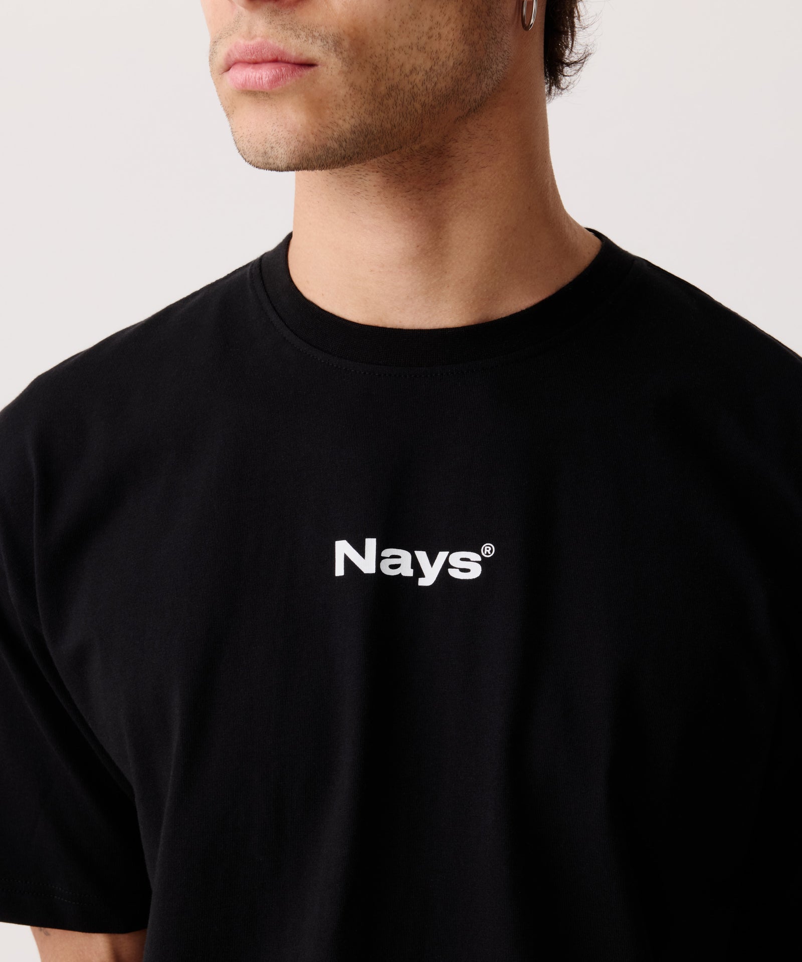 Das Bild zeigt eine Detail-Aufnahme von dem schwarzen Basic T-Shirt getragen von einem Mann.