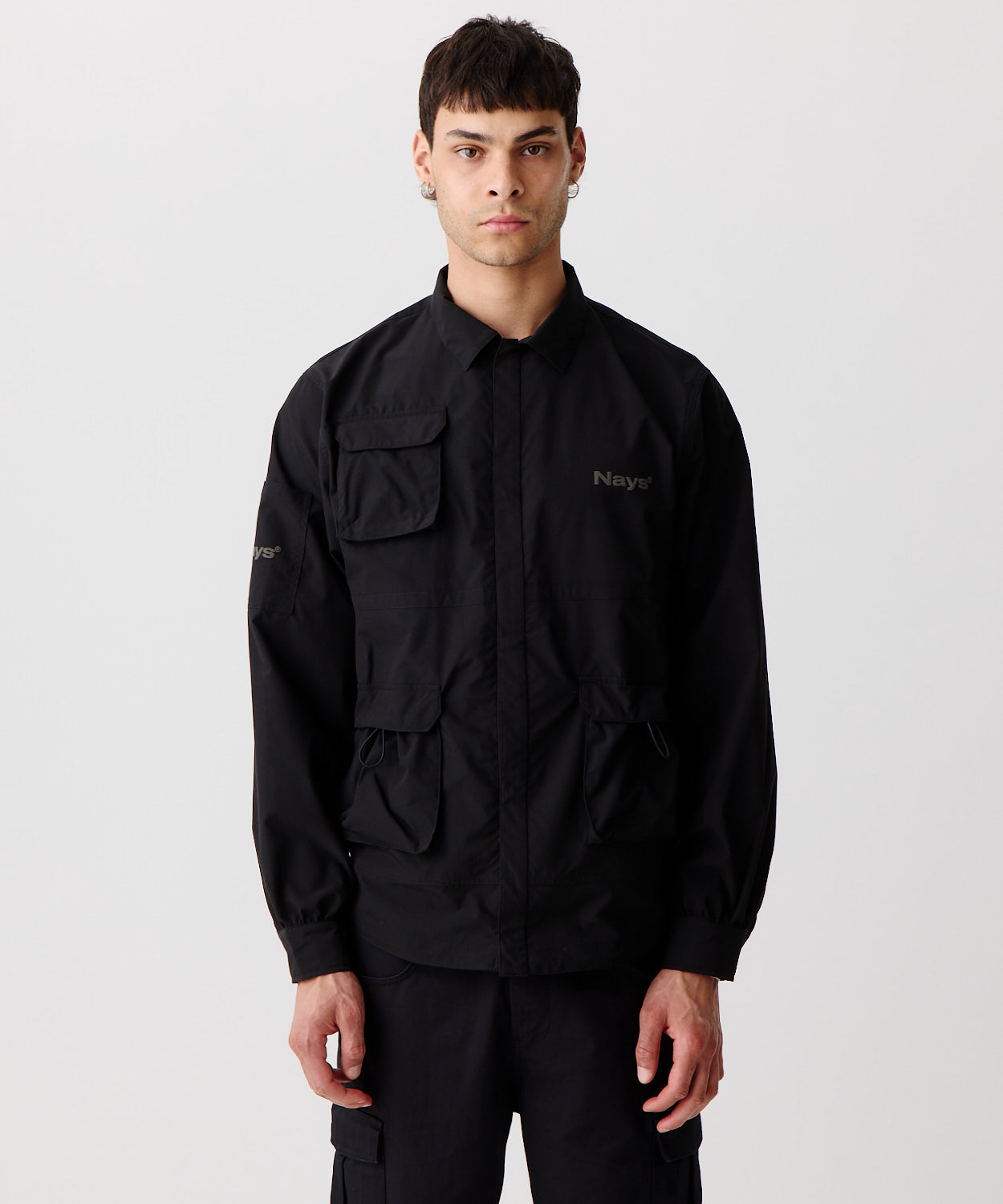 Nays Utility Shirt, eine leichte Shirt-Jacke mit Reverskragen, aufgesetzten Taschen, wasserabweisendem Finish und elastischen Drawstrings getragen von einem Mann in der frontalen Ansicht.