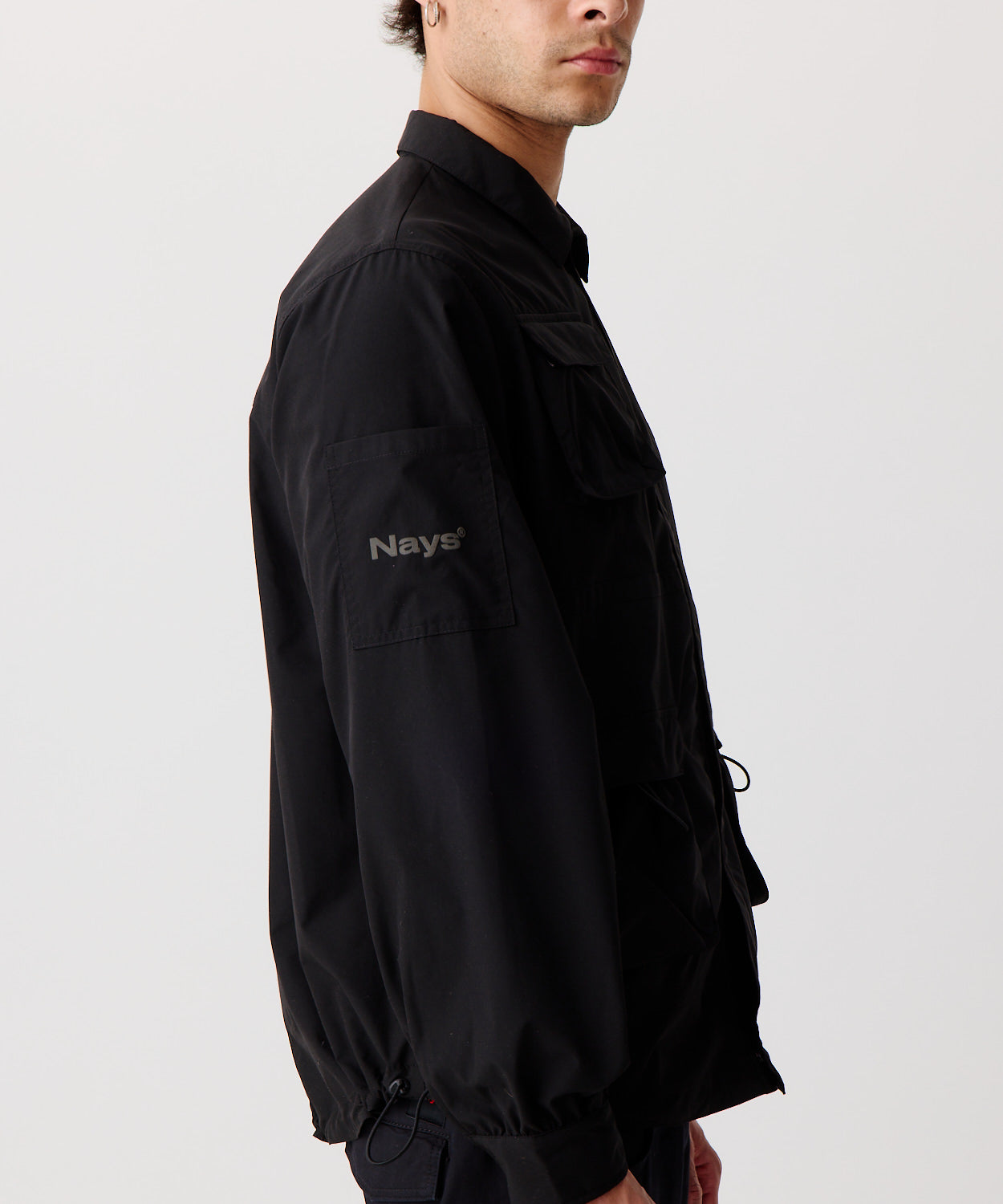 Nays Utility Shirt, eine leichte Shirt-Jacke mit Reverskragen, aufgesetzten Taschen, wasserabweisendem Finish und elastischen Drawstrings getragen von einem Mann im Seitenprofil.