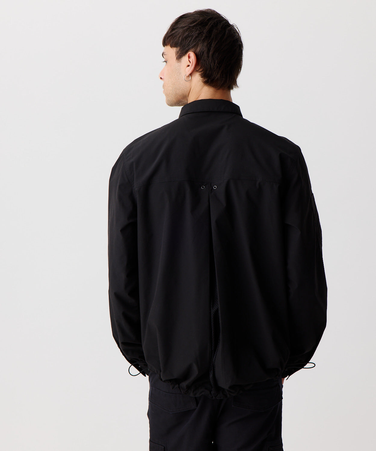Nays Utility Shirt, eine leichte Shirt-Jacke mit Reverskragen, aufgesetzten Taschen, wasserabweisendem Finish und elastischen Drawstrings getragen von einem Mann in der Rückansicht.