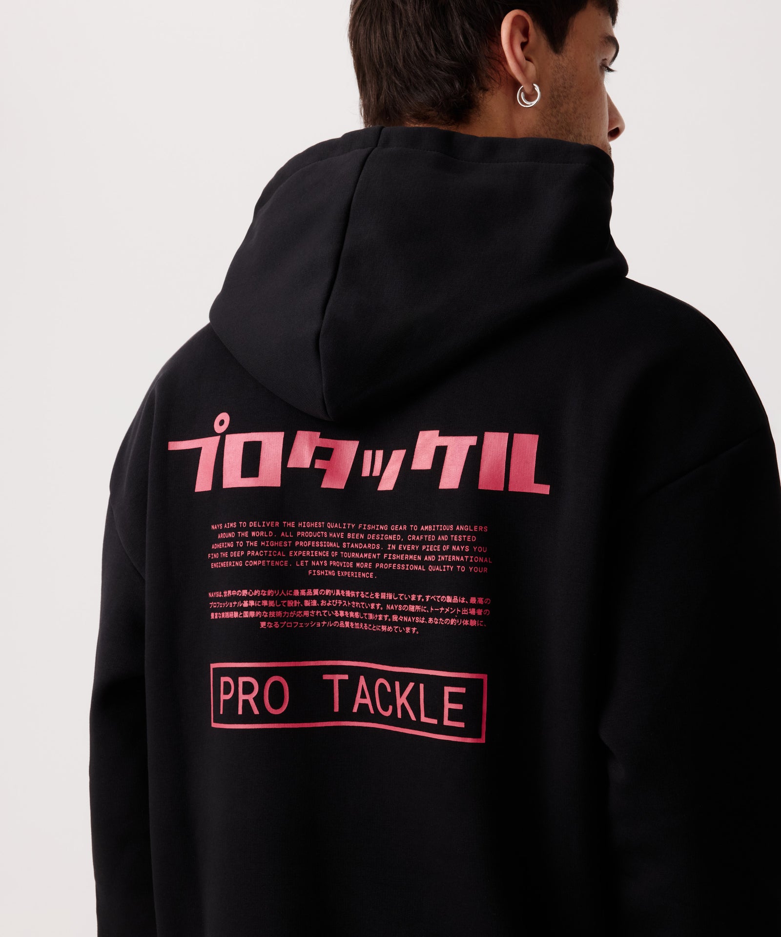 Rückansicht eines Mannes im schwarzen Pro Tackle Kapuzen-Pullover in der Nah-Aufnahme. Gut sichtbar sind Logo-Schriftzügen in Englisch und Japanisch.