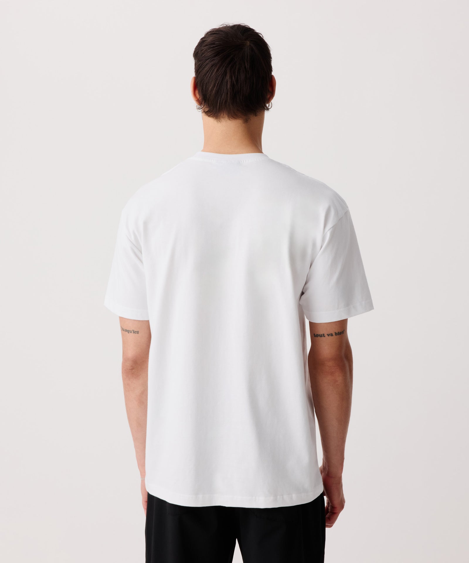 Das Bild zeigt das weiße Basic T-Shirt mit Front-Print getragen von einem Mann in der Rückansicht.