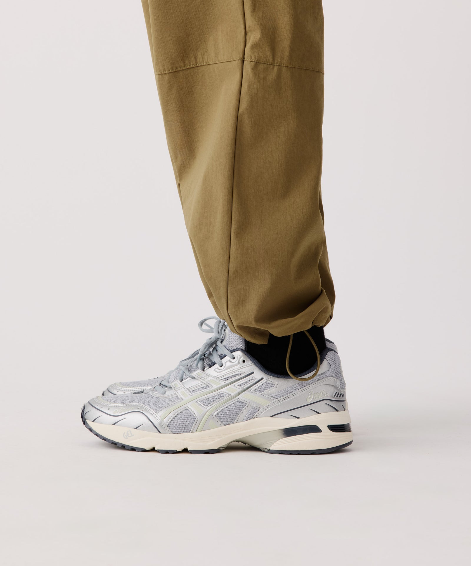 Das Detail-Bild zeigt die Nays Summer Pants getragen von einem Mann. Der Fokus liegt auf den verstellbaren Bündchen und hellen Turnschuhen.