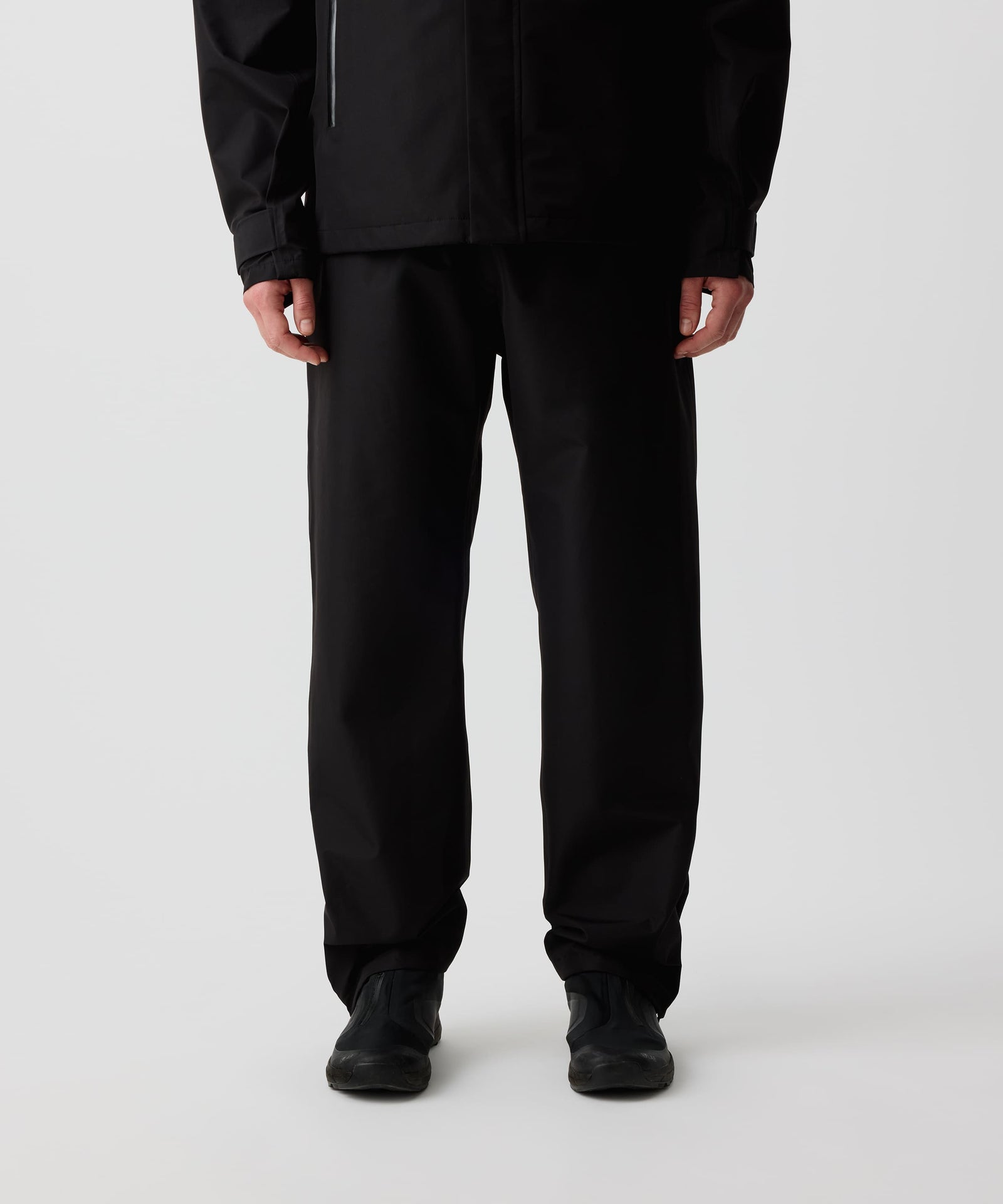 Nays 3L Multifunctional Rain Pants getragen von einer Person, zeigt ergonomische Passform und Reißverschlüsse am Beinsaum für einfaches An- und Ausziehen über Schuhe.