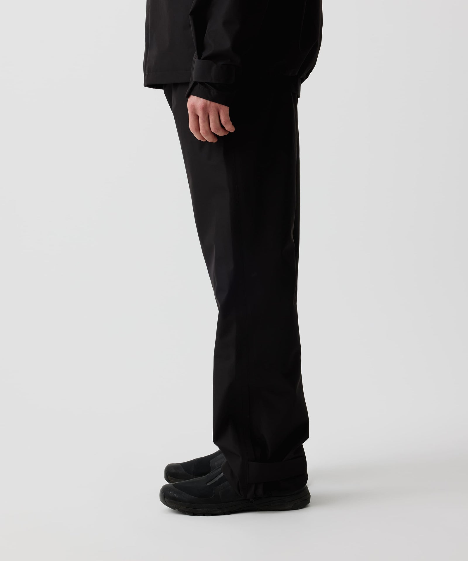 Nays 3L Multifunctional Rain Pants im Seitenprofil getragen von einer Person, zeigt ergonomische Passform und Reißverschlüsse am Beinsaum für einfaches An- und Ausziehen über Schuhe.