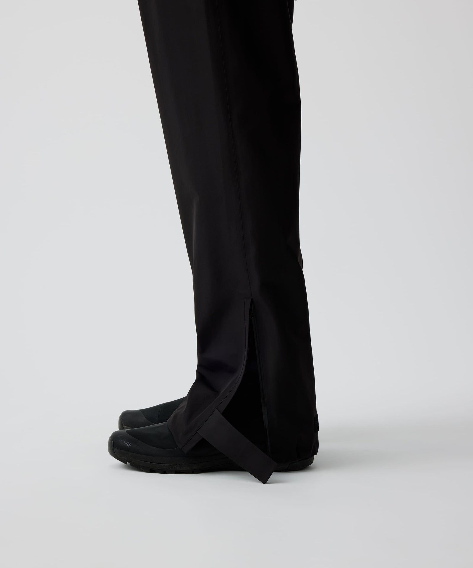 Nays 3L Multifunctional Rain Pants im Seitenprofil getragen von einer Person, zeigt ergonomische Passform und Reißverschlüsse am Beinsaum für einfaches An- und Ausziehen über Schuhe.