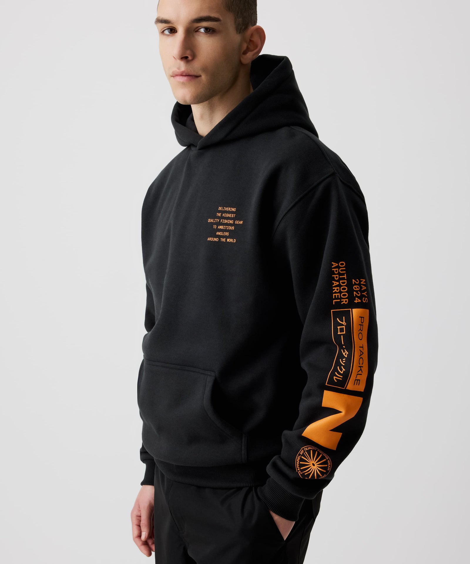 Mann trägt Nays Quote Hoodie mit auffälligem orangefarbenem Nays-Print im Halbseiten Profil. Schwarzer Hoodie aus Baumwoll-Polyester-Mix, ideal für den Alltag und kühleres Wetter.