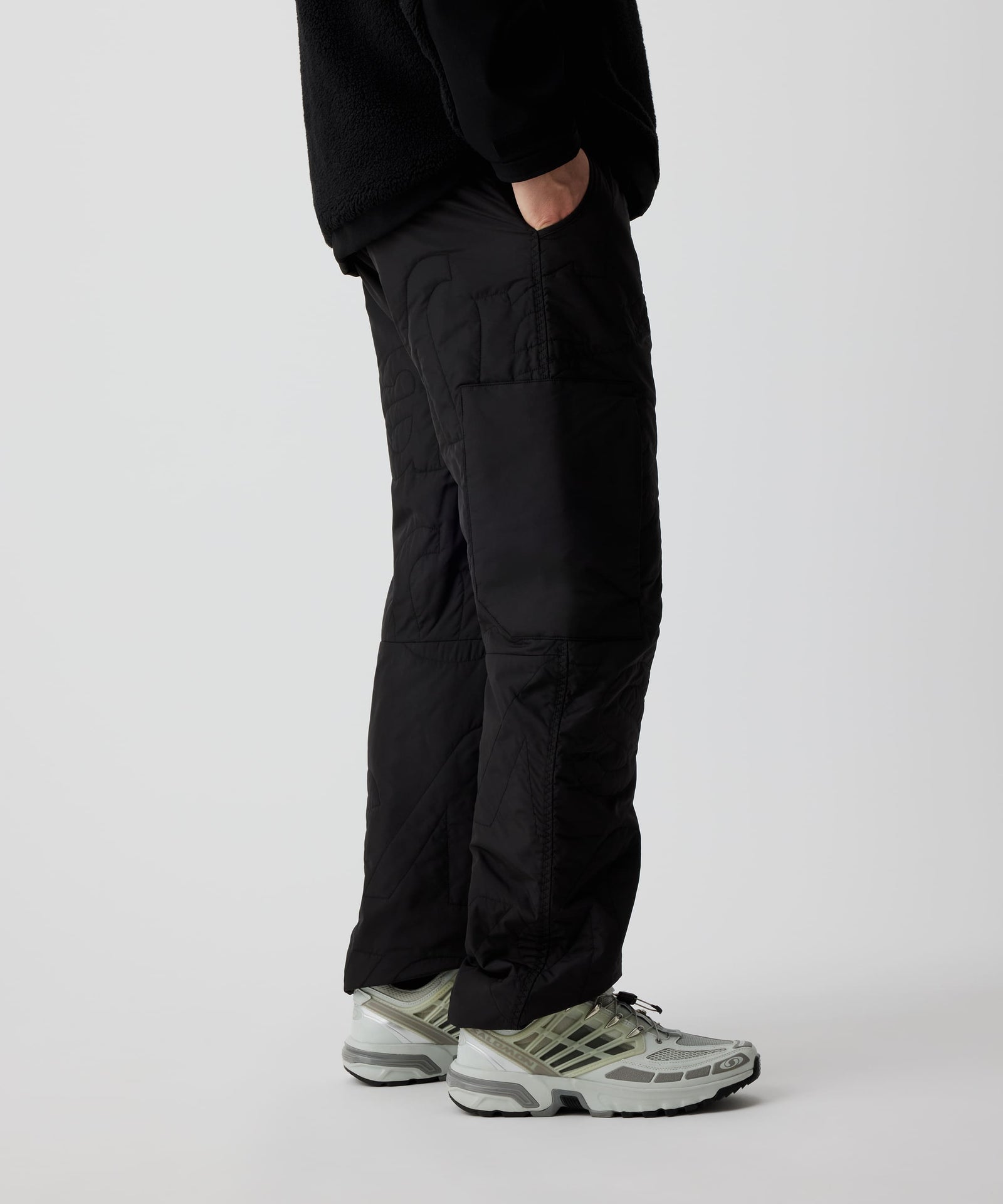 Person trägt Nays Thermo Hose mit elastischem Bund und mehreren Taschen, ideal für kalte Temperaturen und Outdoor-Aktivitäten. Sichtbar sind die Steppoptik und weiße Sneakers.