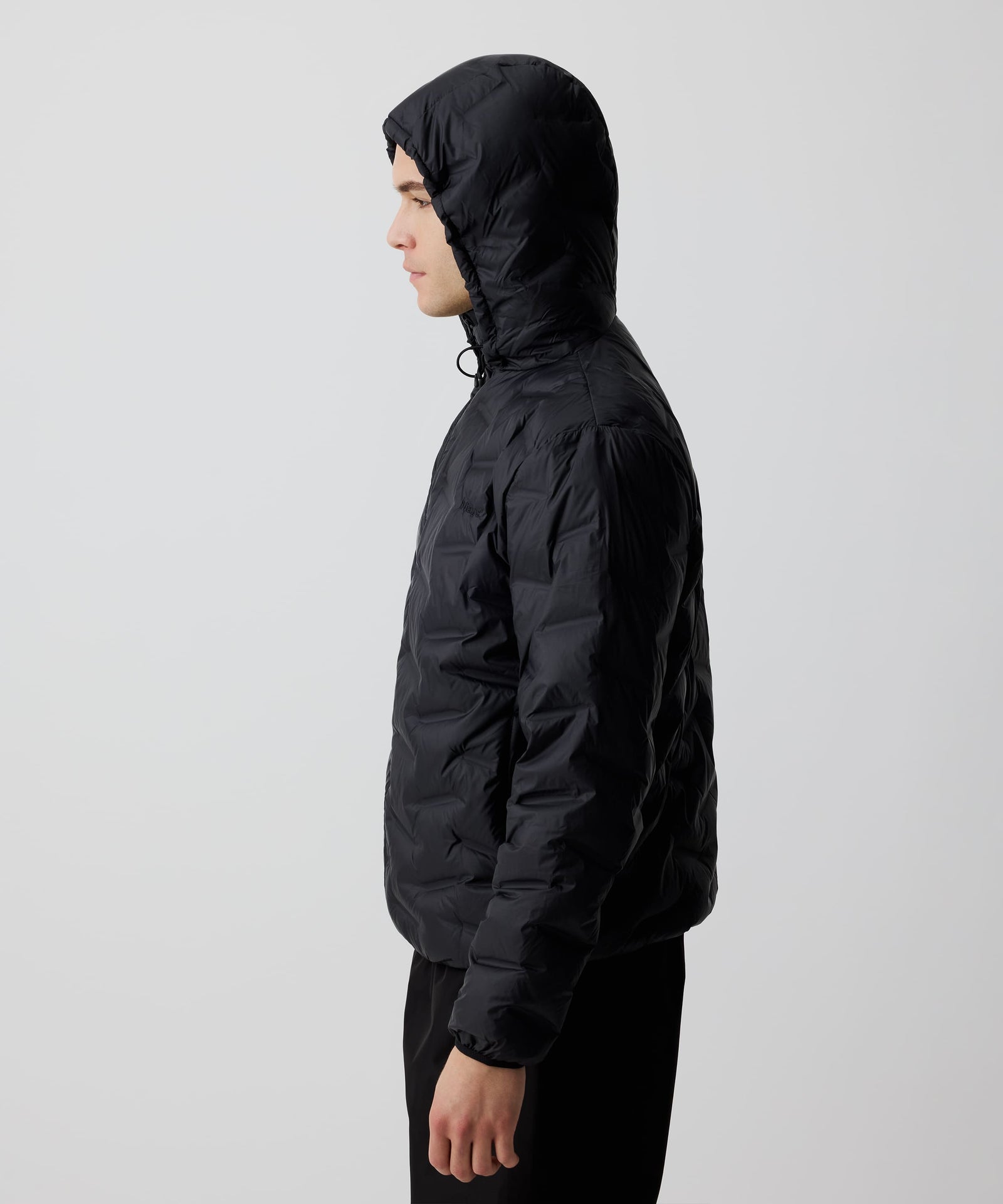 Ein Mann trägt die Nays Lightweight Down Jacket mit aufgesetzter Kapuze im Seitenprofil. Ideal für kalte Tage und Outdoor-Abenteuer.