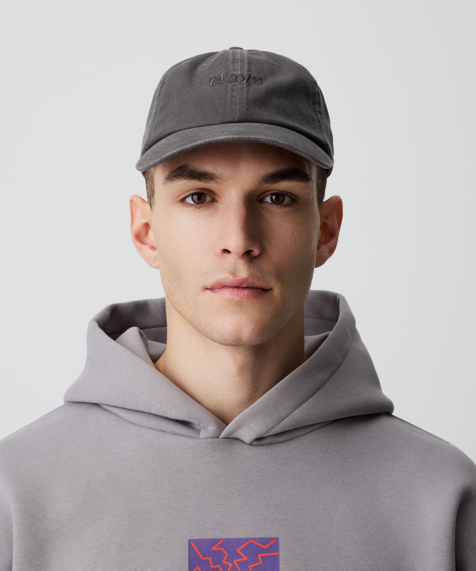 Mann trägt Nays Sports Cap Washed mit charakteristischem Washed-Effekt und verstellbarer Passform, kombiniert mit grauem Hoodie für lässigen, zeitlosen Stil.