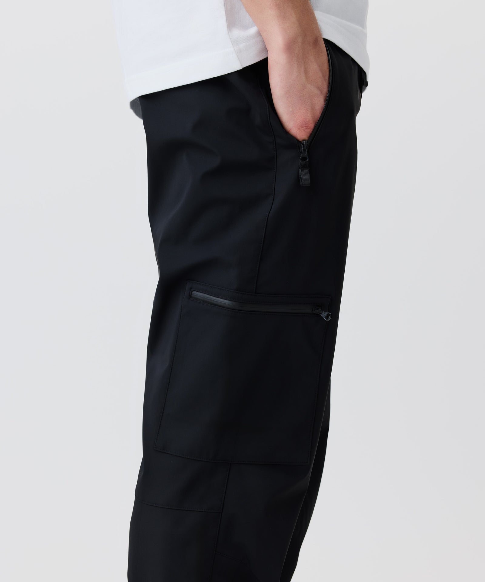 In diesem Bild-Ausschnitt im Seiten-Profil erkennt man die aufgesetzte Cargo-Tasche. Eine Hand steckt in der Seitentaschen. Beide Taschen besitzen Reißverschlüsse.