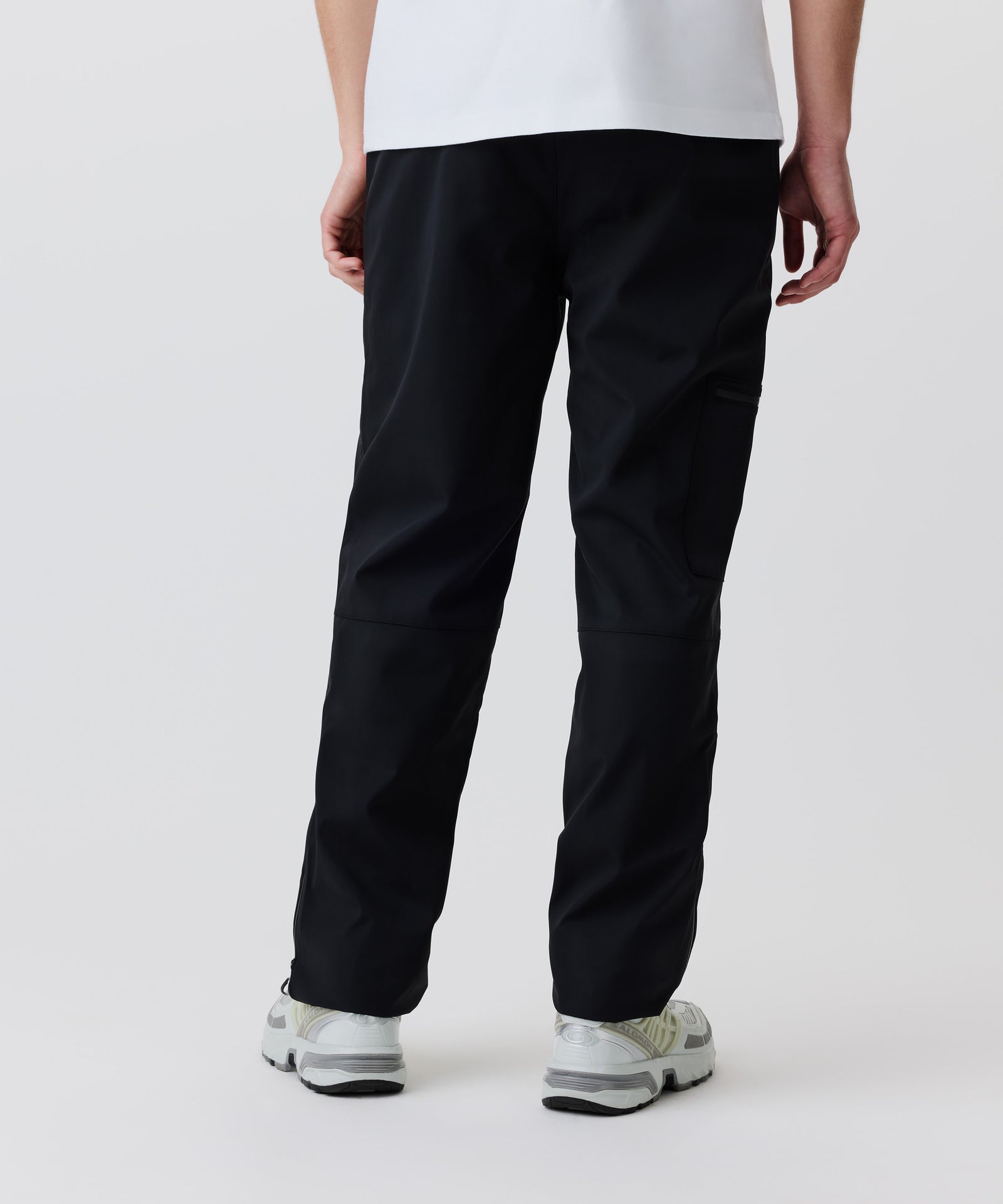Auf dem Bild erkennt man unsere Soft-Shell-Hose in der Rückansicht. Der Mann trägt dazu ein weißes T-Shirt und helle Turnschuhe.