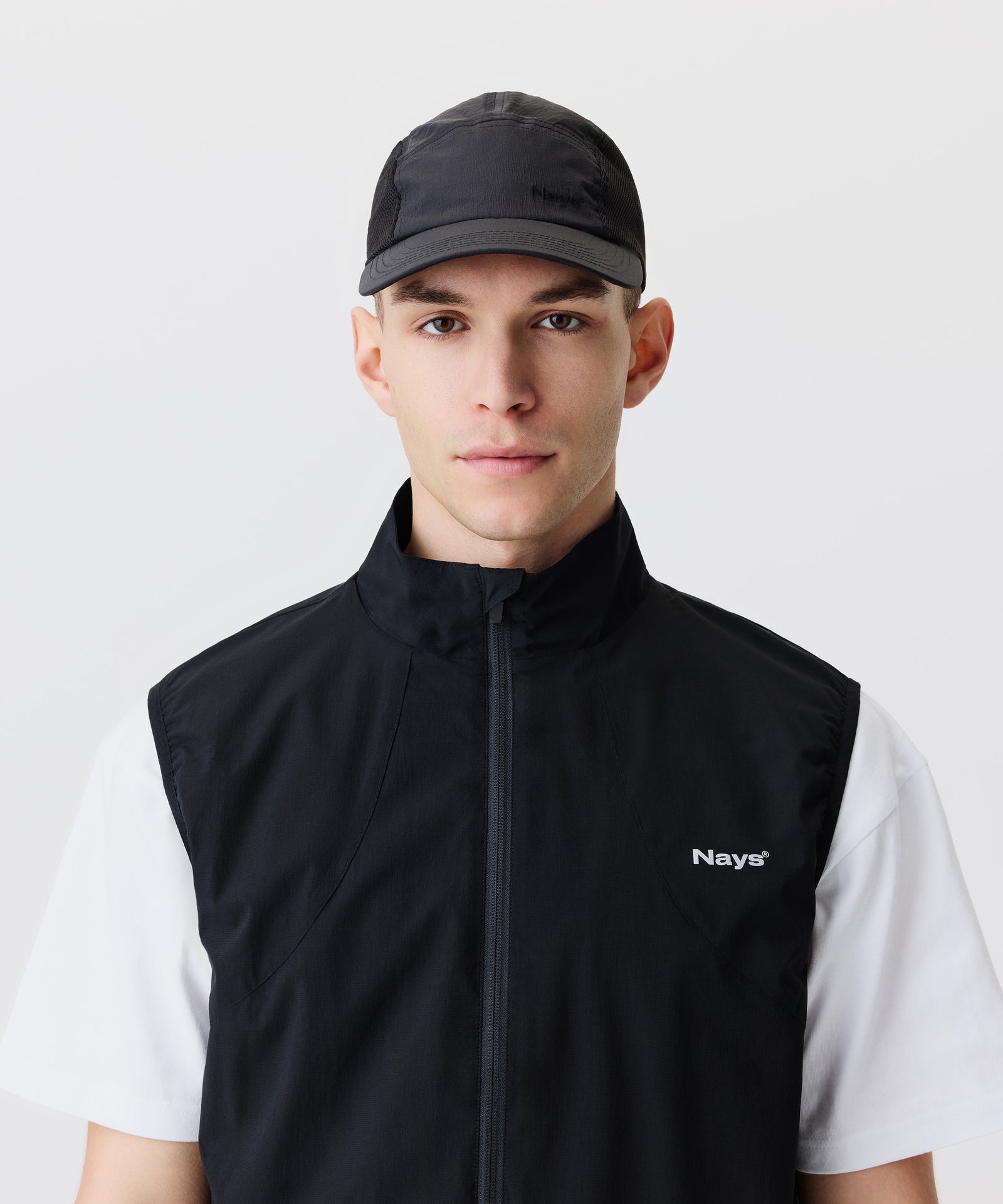 Auf dem Bild-Ausschnitt trägt ein Mann unsere schwarze Schirm-Mütze. Dazu trägt er ein weißen T-Shirt und eine schwarze Weste mit weißem Logo auf der Brust.