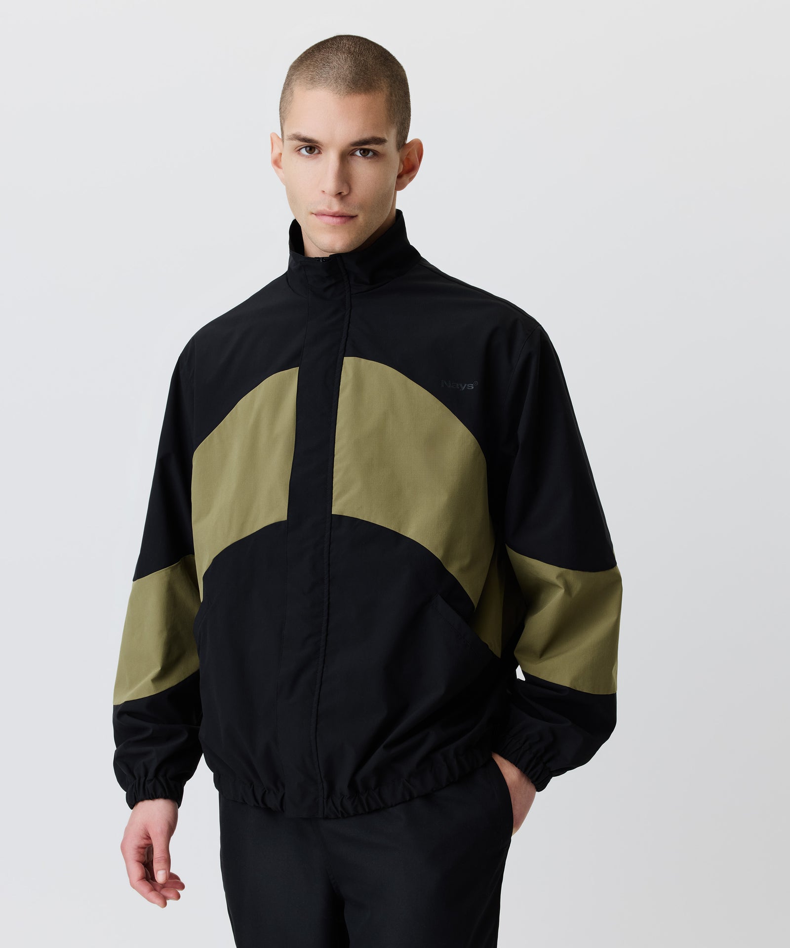 Auf dem Bild trägt der Mann den Wind-Breaker in Kombination mit einer schwarzen Hose.