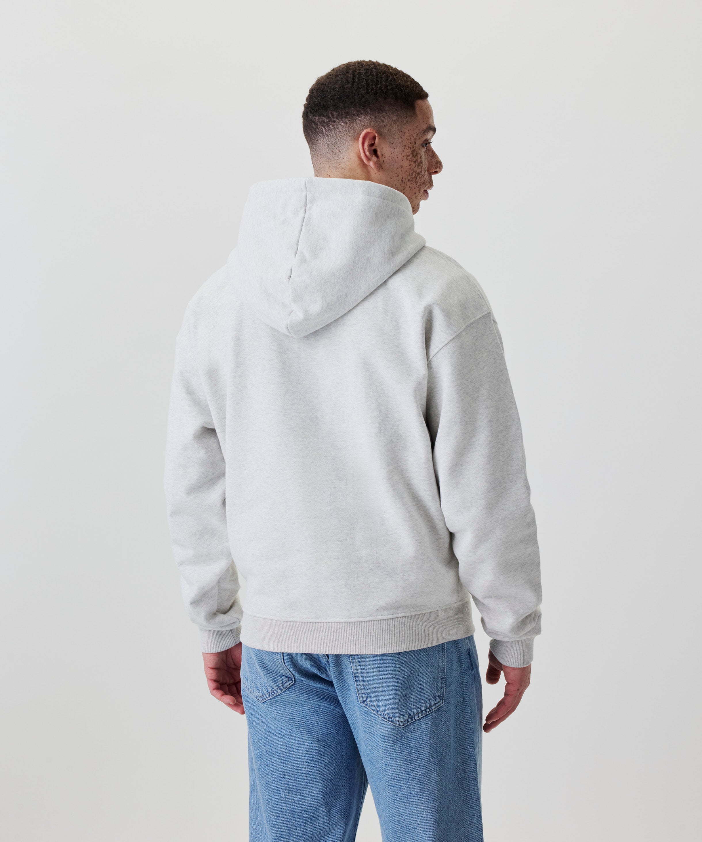 Rückansicht eines hellgrauen Oversize-Hoodies mit Kapuze und elastischem Saum.