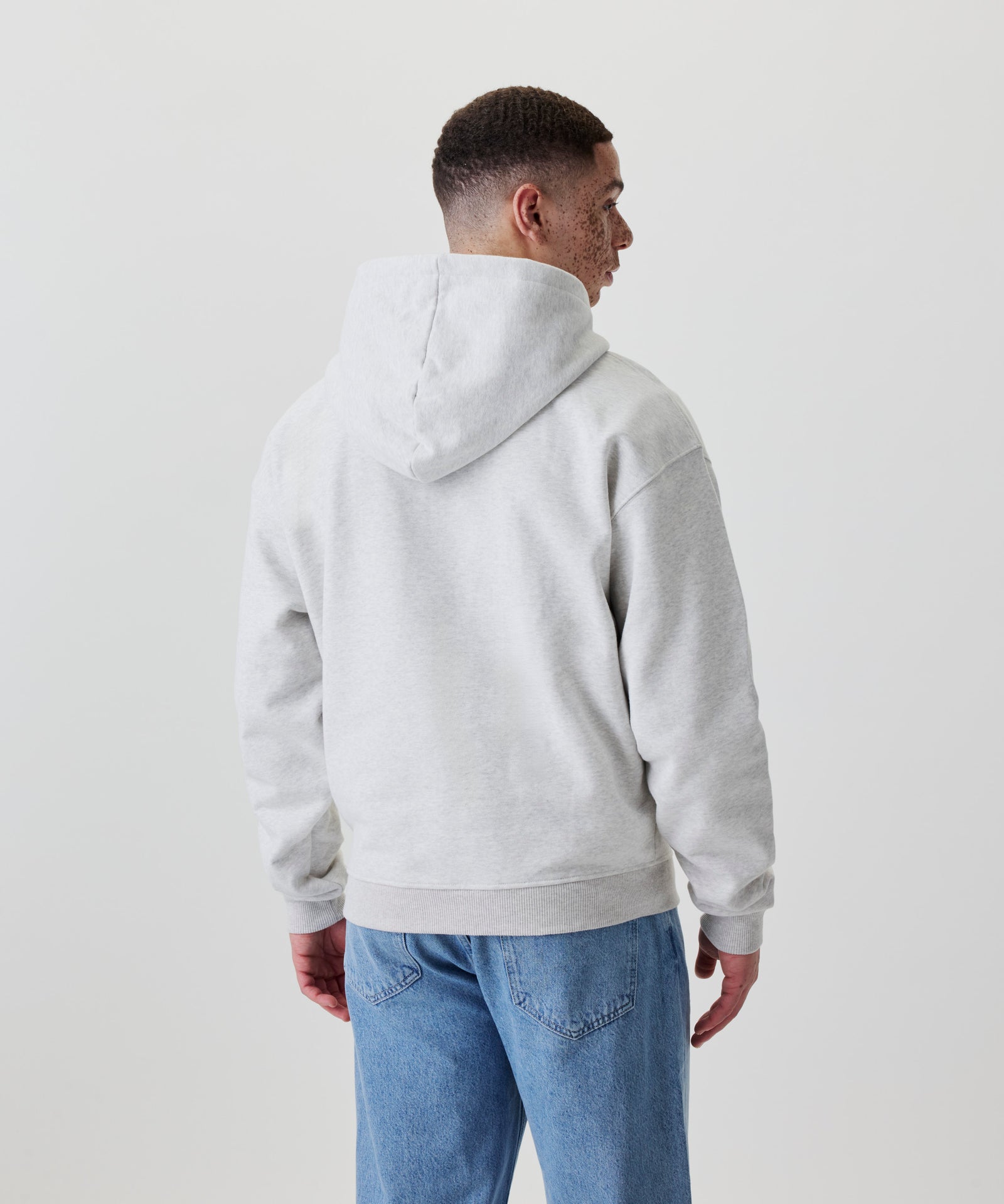 Rückansicht eines hellgrauen Oversize-Hoodies mit Kapuze und elastischem Saum.