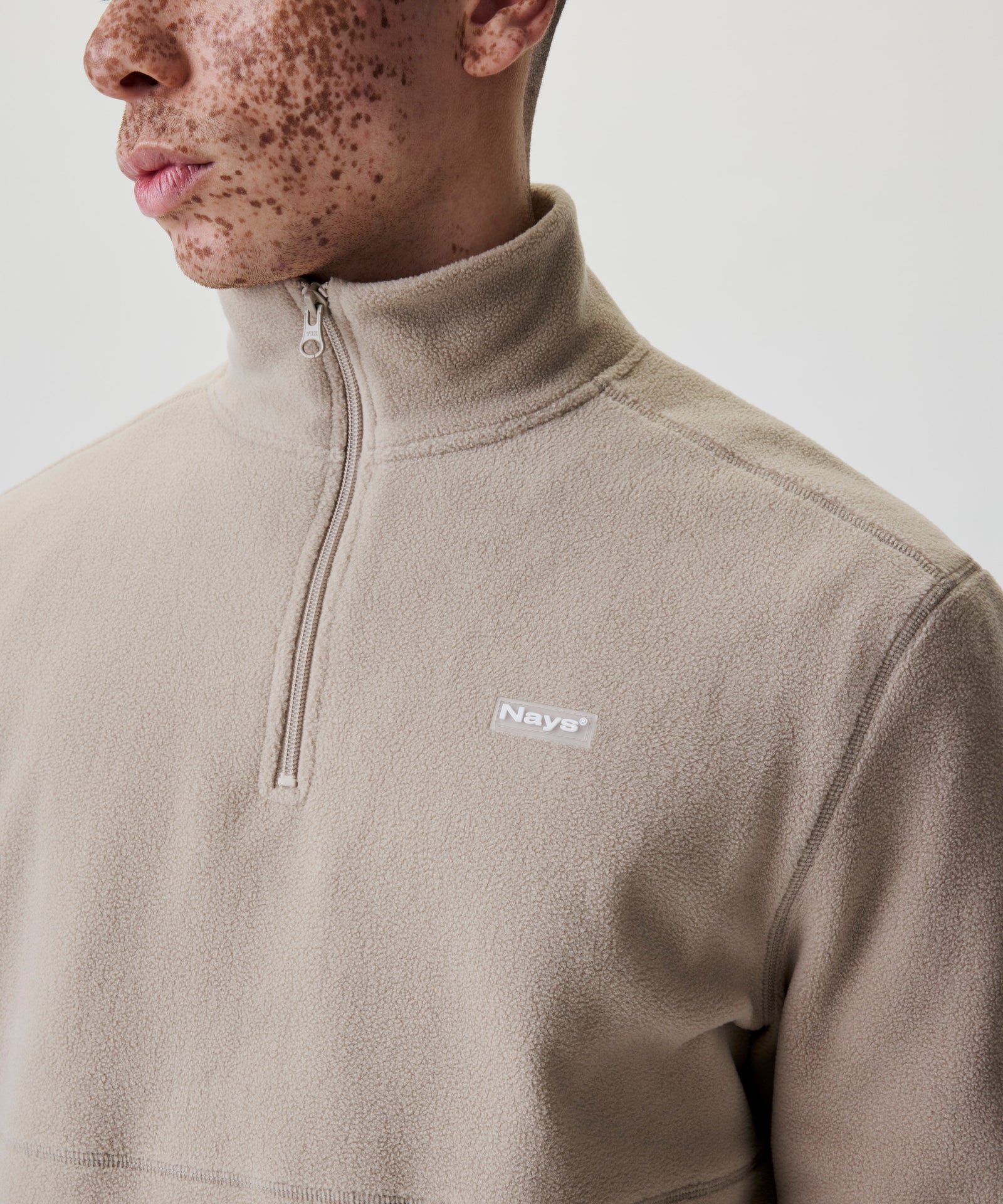 Detailansicht Kragen und Reißverschluss beiger Fleece-Pullover.