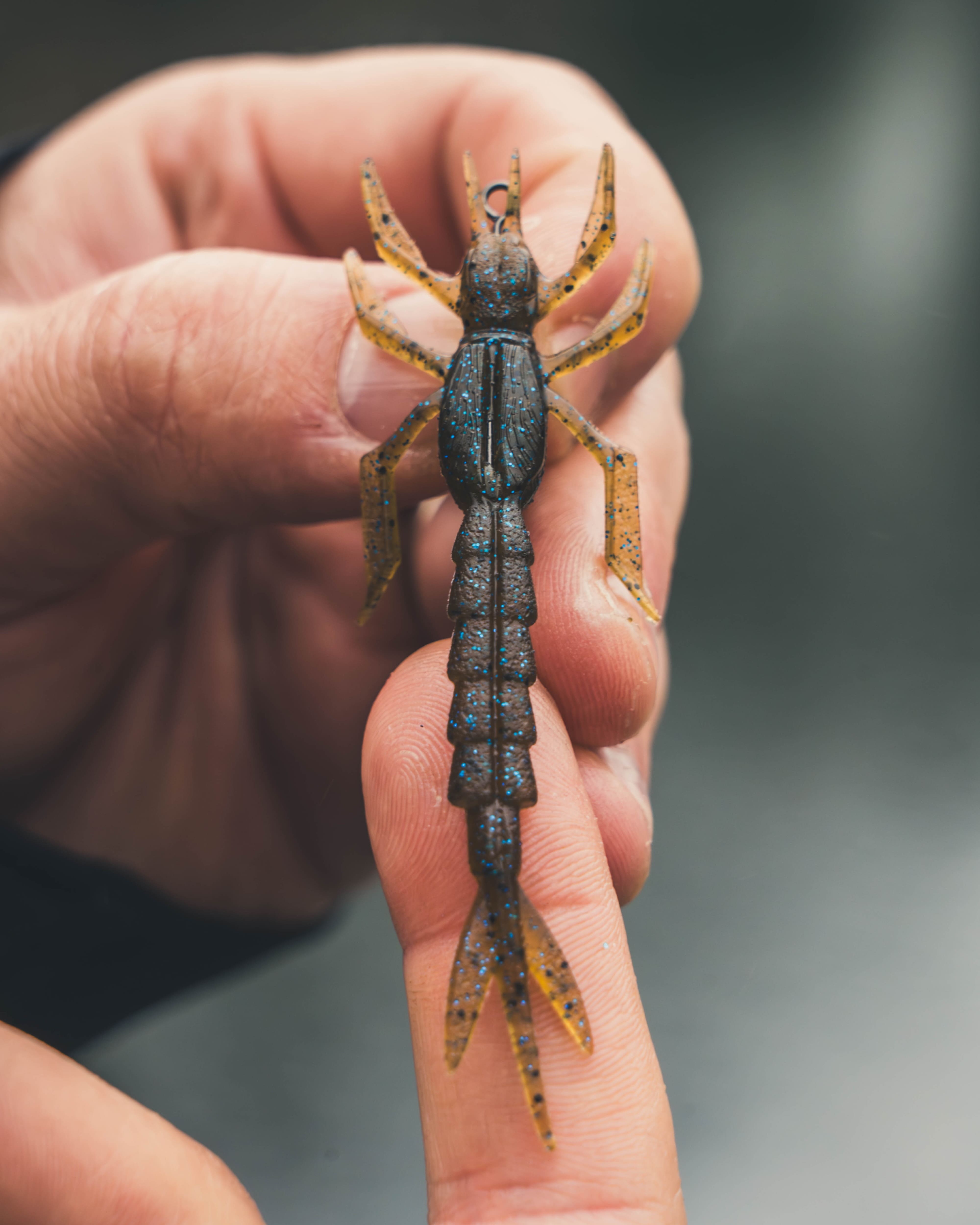 Gummiköder in Krebsform als Creature Bait für das Finesse-Angeln, gehalten in einer Hand zur Detailansicht von Beinen und Schwanzsegment.