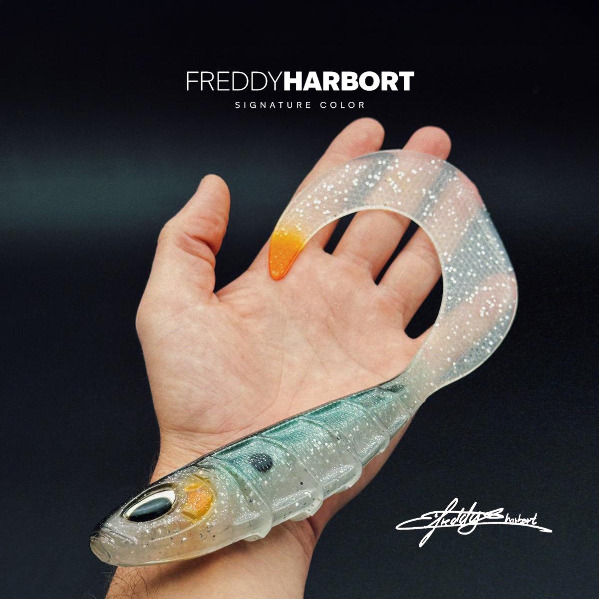 Nays GHST 100 - Freddy Harbort: Hand hält weichen Swimbait mit silbernen Glitzer, grünem Rücken, orange Spitze. Perfekt für Hechte, entworfen von Turnierangler Freddy Harbort.