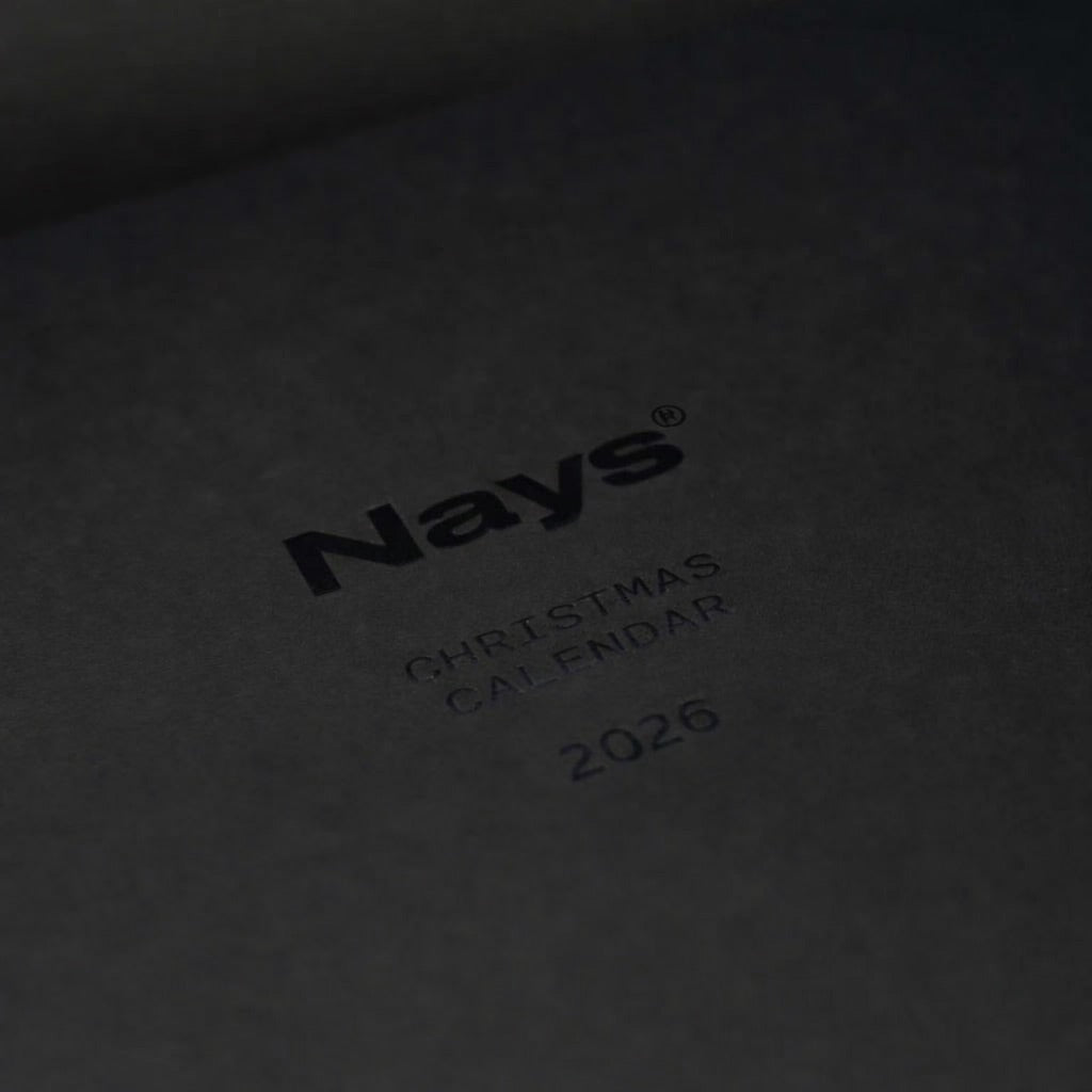 Nays Adventskalender 2026 auf schwarzer Oberfläche, schwarzer Text sichtbar. Enthält 24 exklusive Angelköder und Zubehör, ideal für Angler und Nays-Fans.