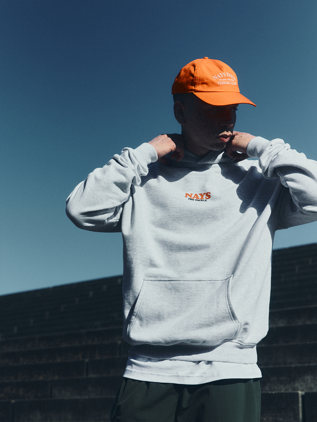 Model in grauen NAYS College Print Hoodie im Velodrom Berlin.