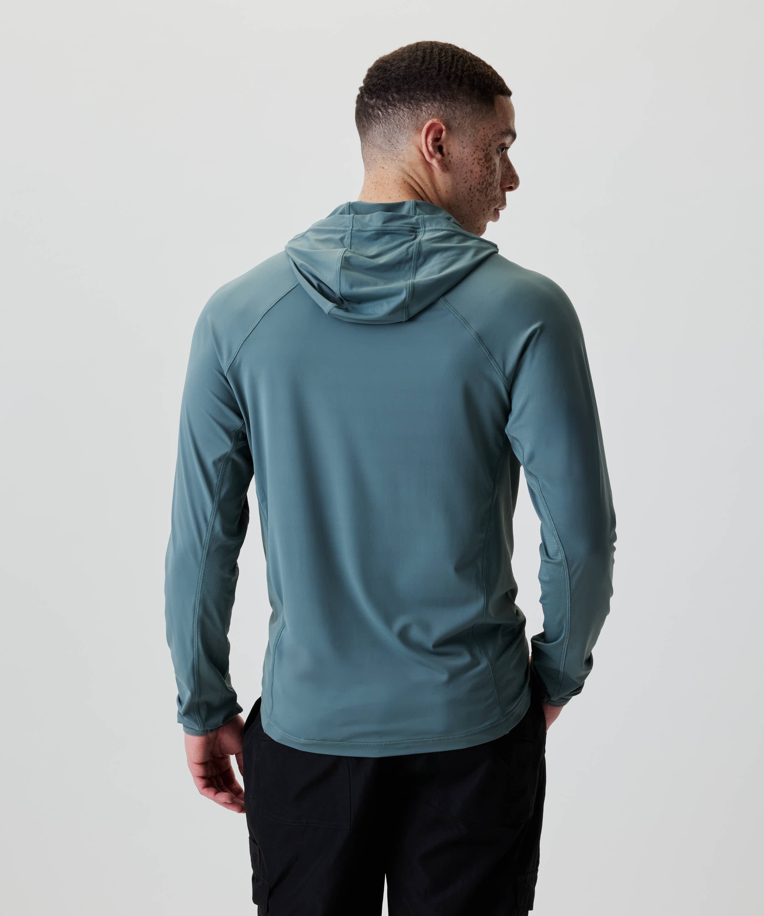 Ein junger Mann trägt das Nays UV 50+ Hooded Longsleeve mit Raglanärmeln und Kapuze, ideal für Sonnenschutz und Bewegungsfreiheit.