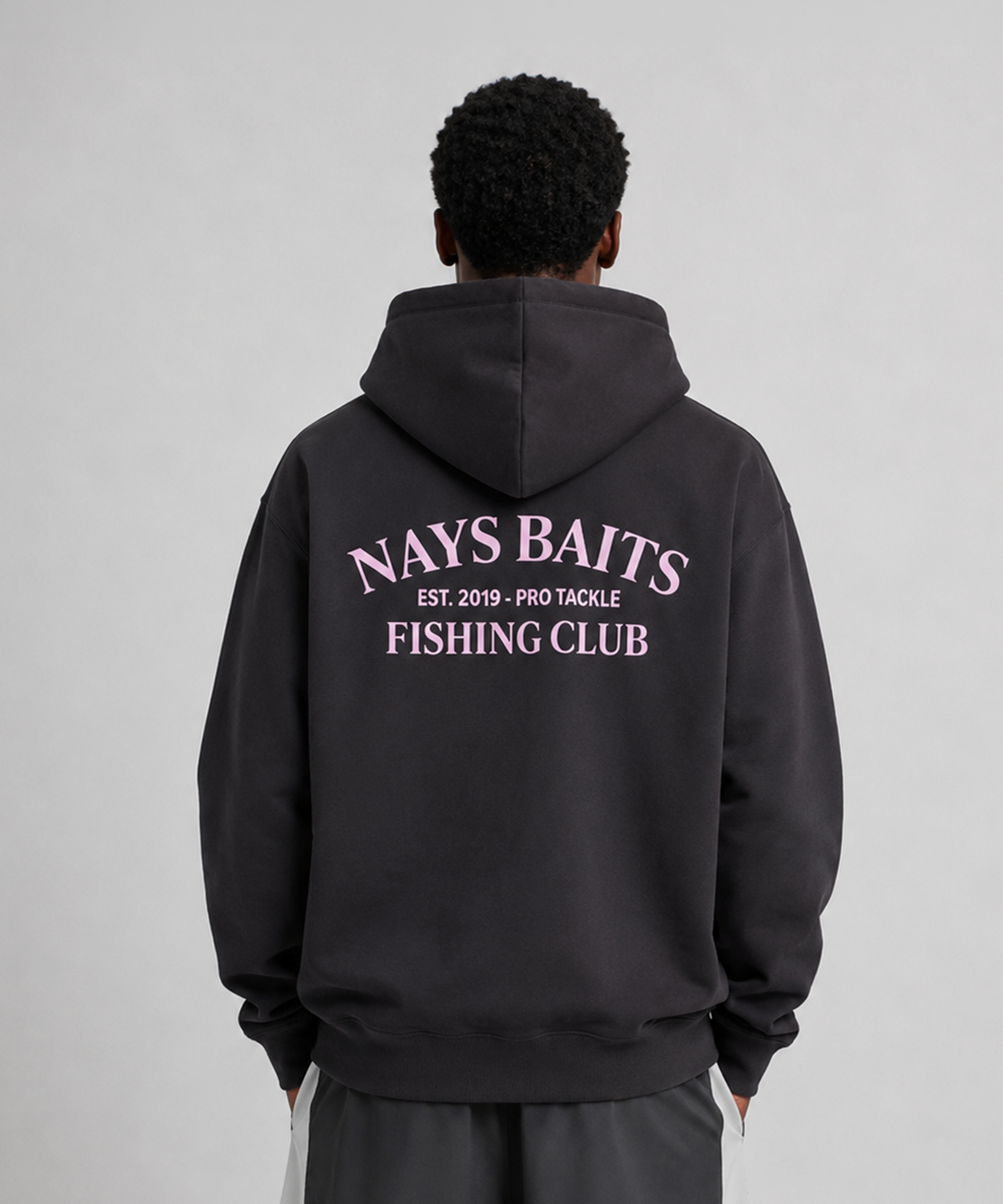 Model trägt Nays Baits Fishing Club Hoodie in Schwarz – Detailansicht der Rückseite mit rosa Logo-Print.
