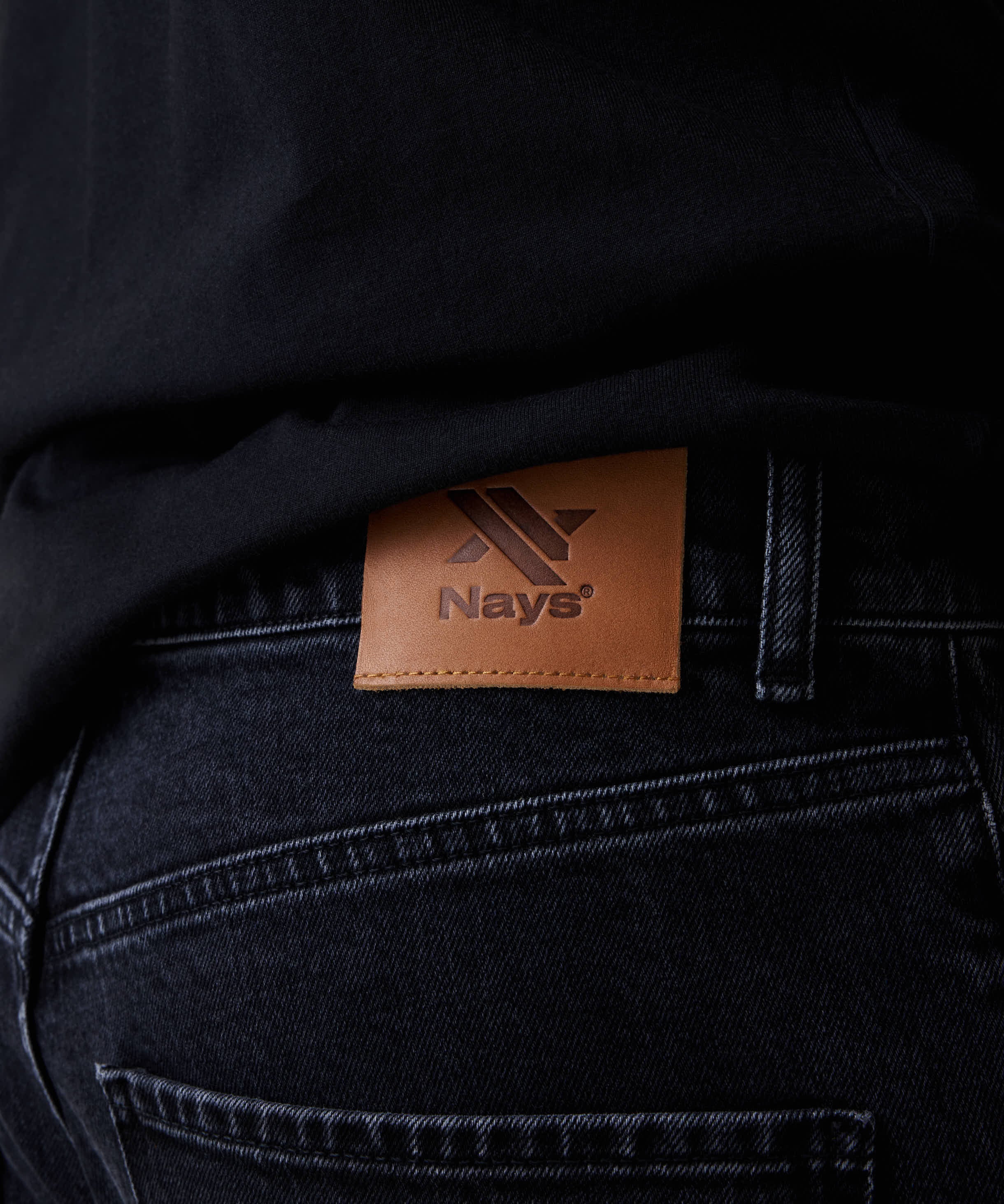 Nahaufnahme der Nays Regular Fit Jeans mit braunem Logo-Patch am Bund, zeigt das klassische 5-Pocket-Design und hochwertige Verarbeitung aus elastischem Denim.