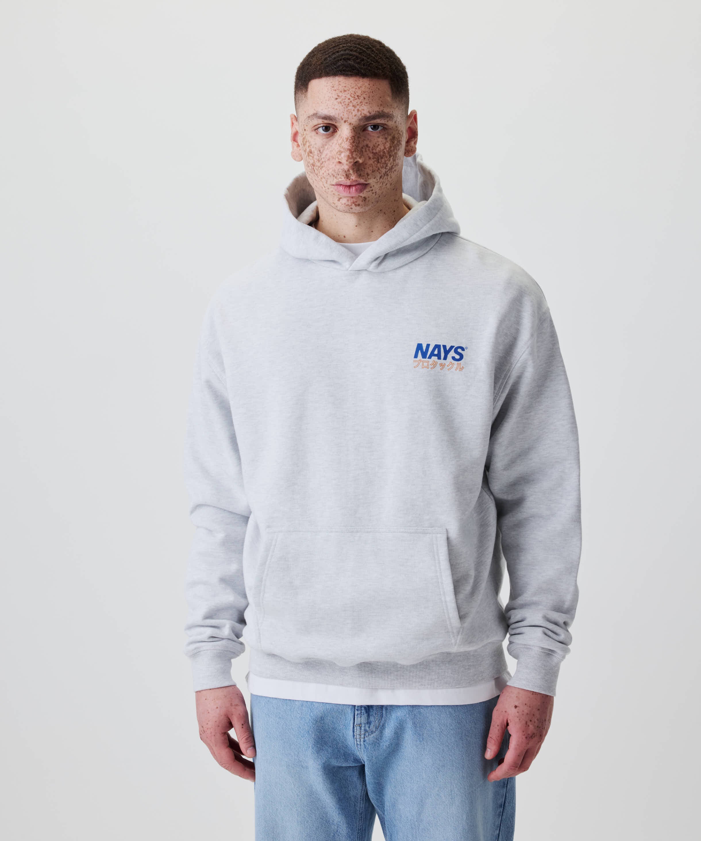 Ein junger Mann trägt den Nays Pro Tackle International Hoodie, gekennzeichnet durch das NAYS-Logo auf der Brust und lässigem, komfortablem Design.