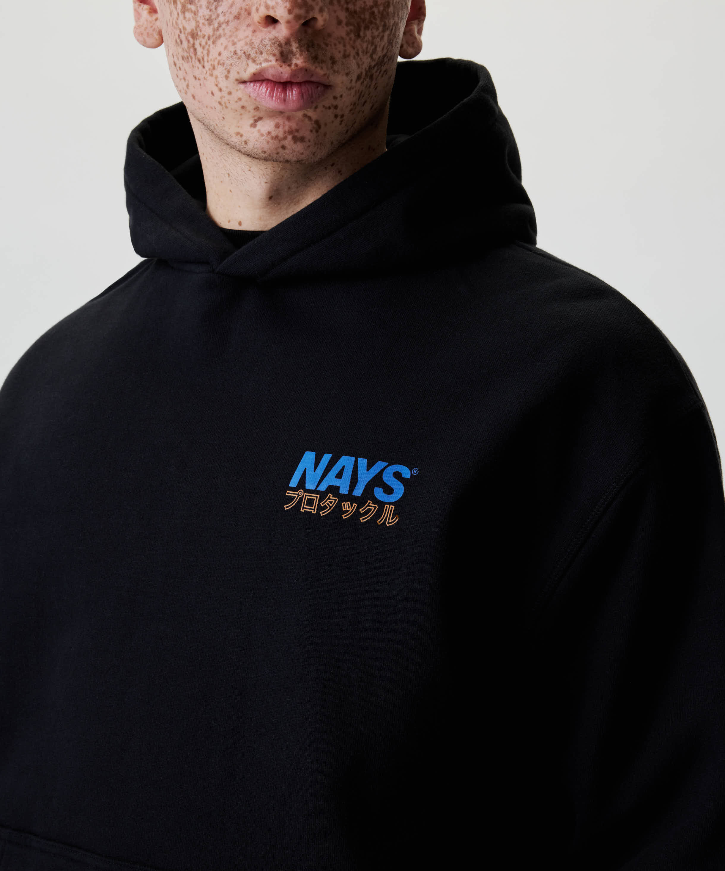 Nahaufnahme des Nays Pro Tackle International Hoodie mit blauem Logo und japanischem Text auf der Brust, zeigt lässigen Stil und komfortables Baumwollmaterial.