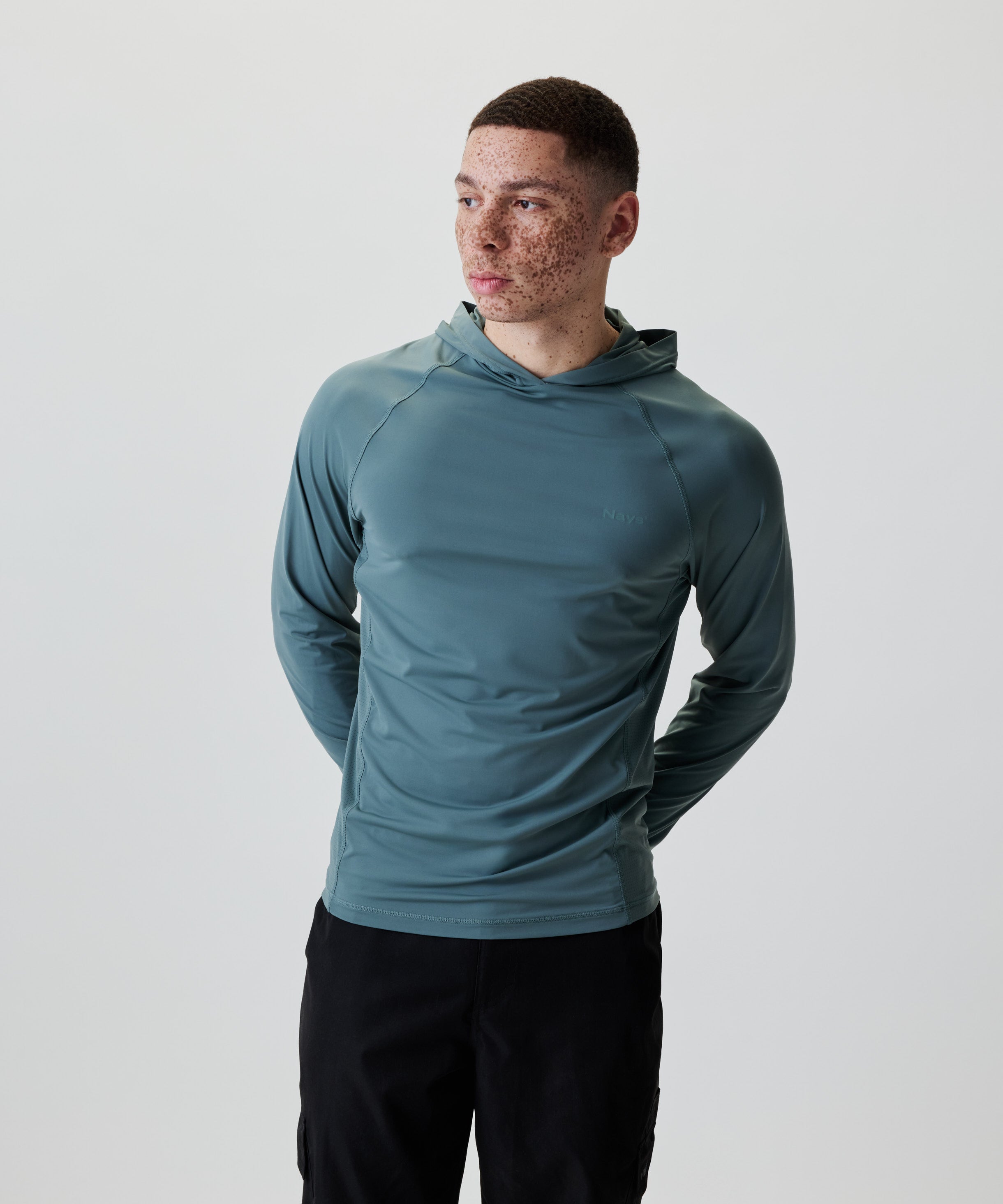 Ein junger Mann trägt das Nays UV 50+ Hooded Longsleeve mit Raglanärmeln und Kapuze, ideal für Sonnenschutz bei Aktivitäten.