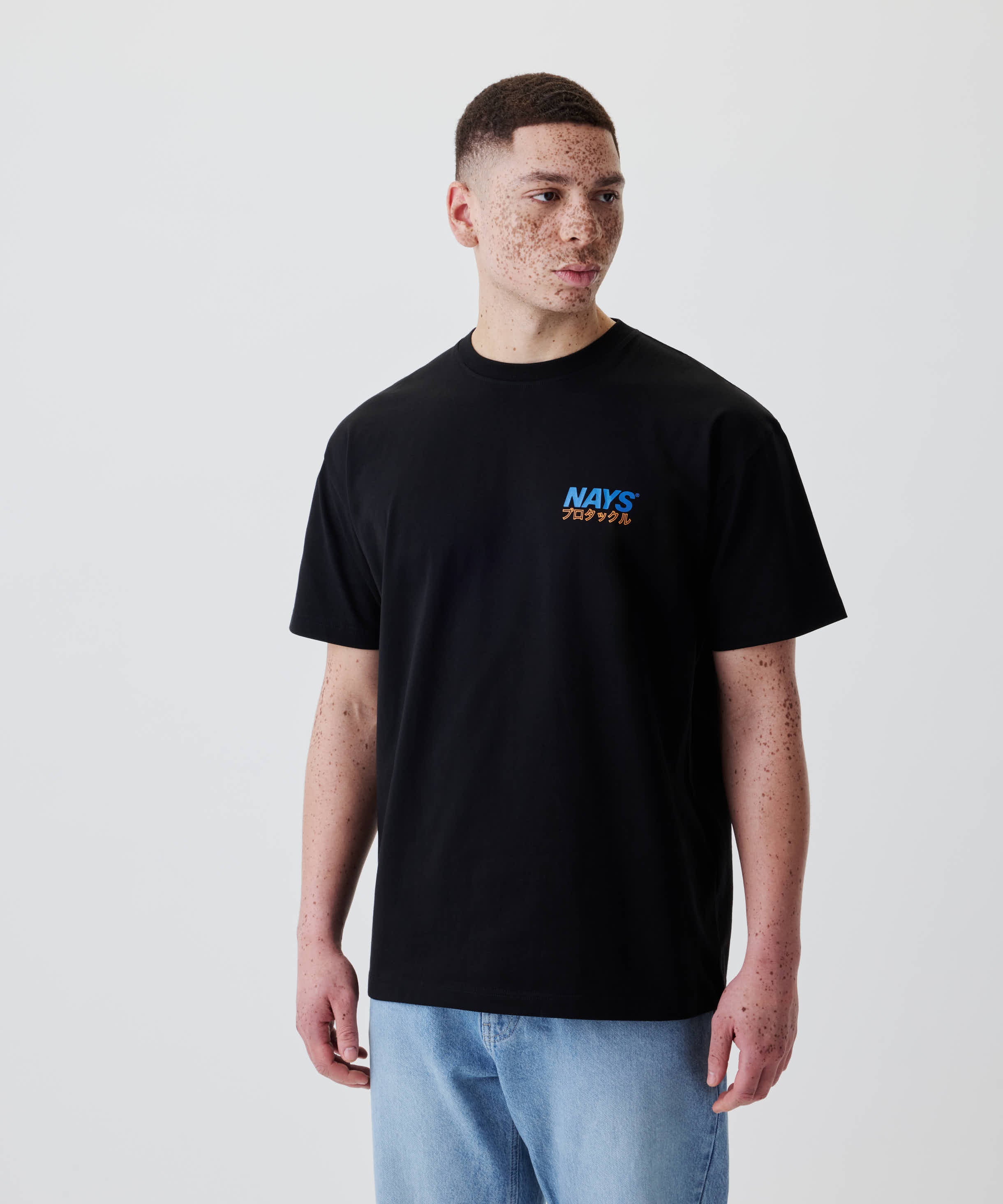 Ein junger Mann trägt das Nays Pro Tackle International Tee mit kleinem Brustprint, perfekt für Alltag und Freizeit, aus 100% Baumwolle.