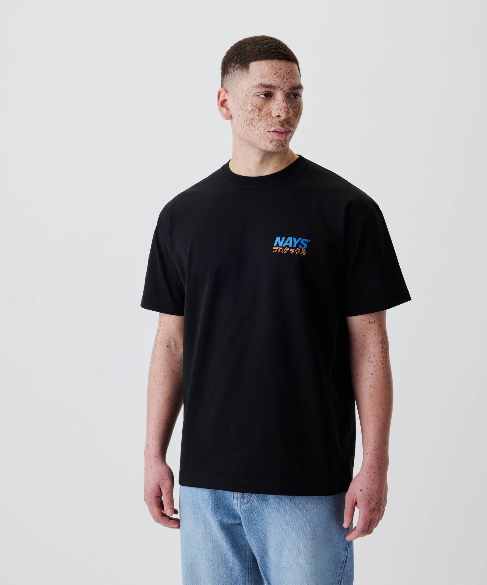 Ein junger Mann trägt das Nays Pro Tackle International Tee mit kleinem Brustprint, perfekt für Alltag und Freizeit, aus 100% Baumwolle.