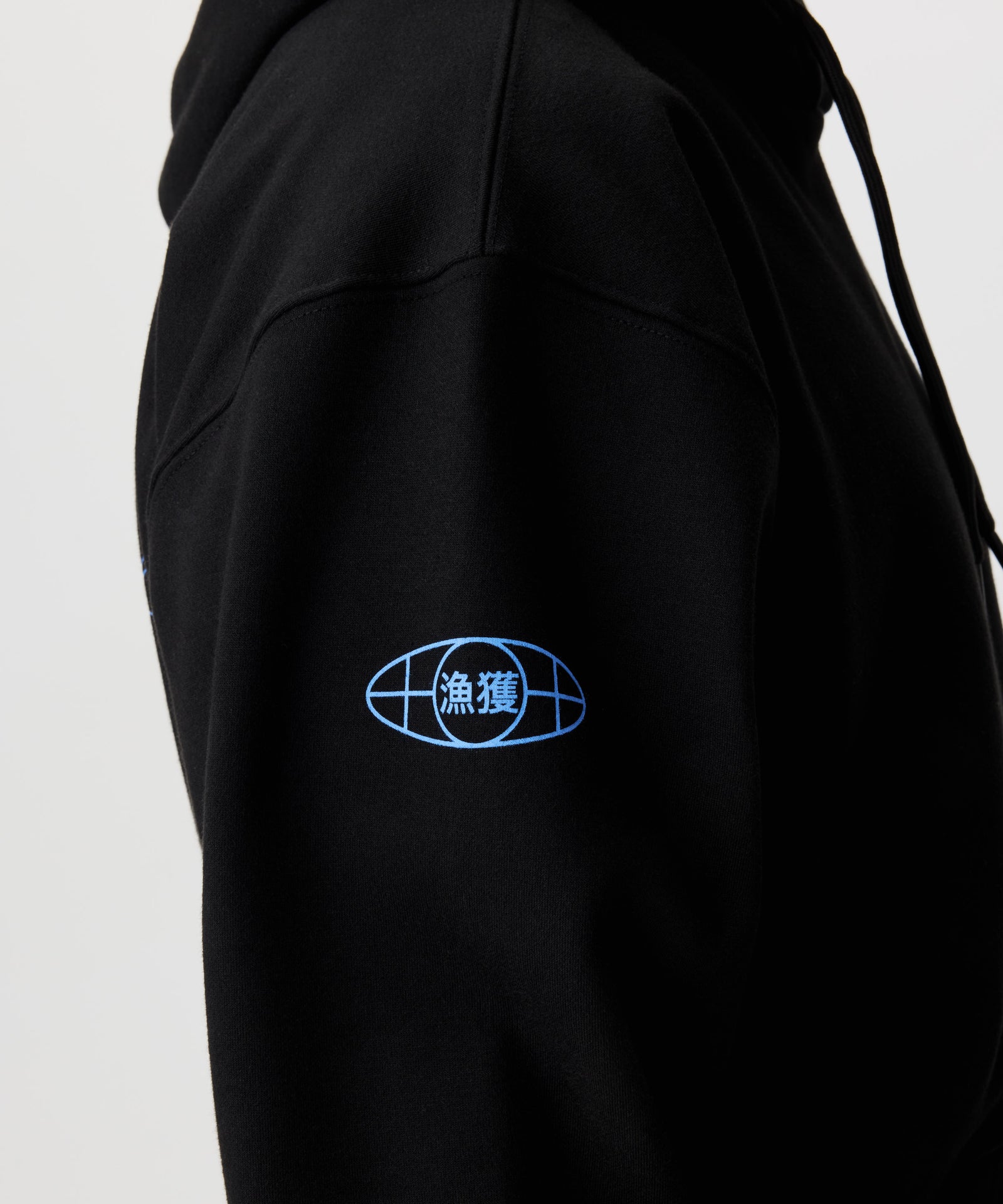 Detailansicht, Mann im Seitenprofil im schwarzen Kapuzen-Pullover. Fokus auf blauen Aermel-Print, der an einen Globus erinnert.