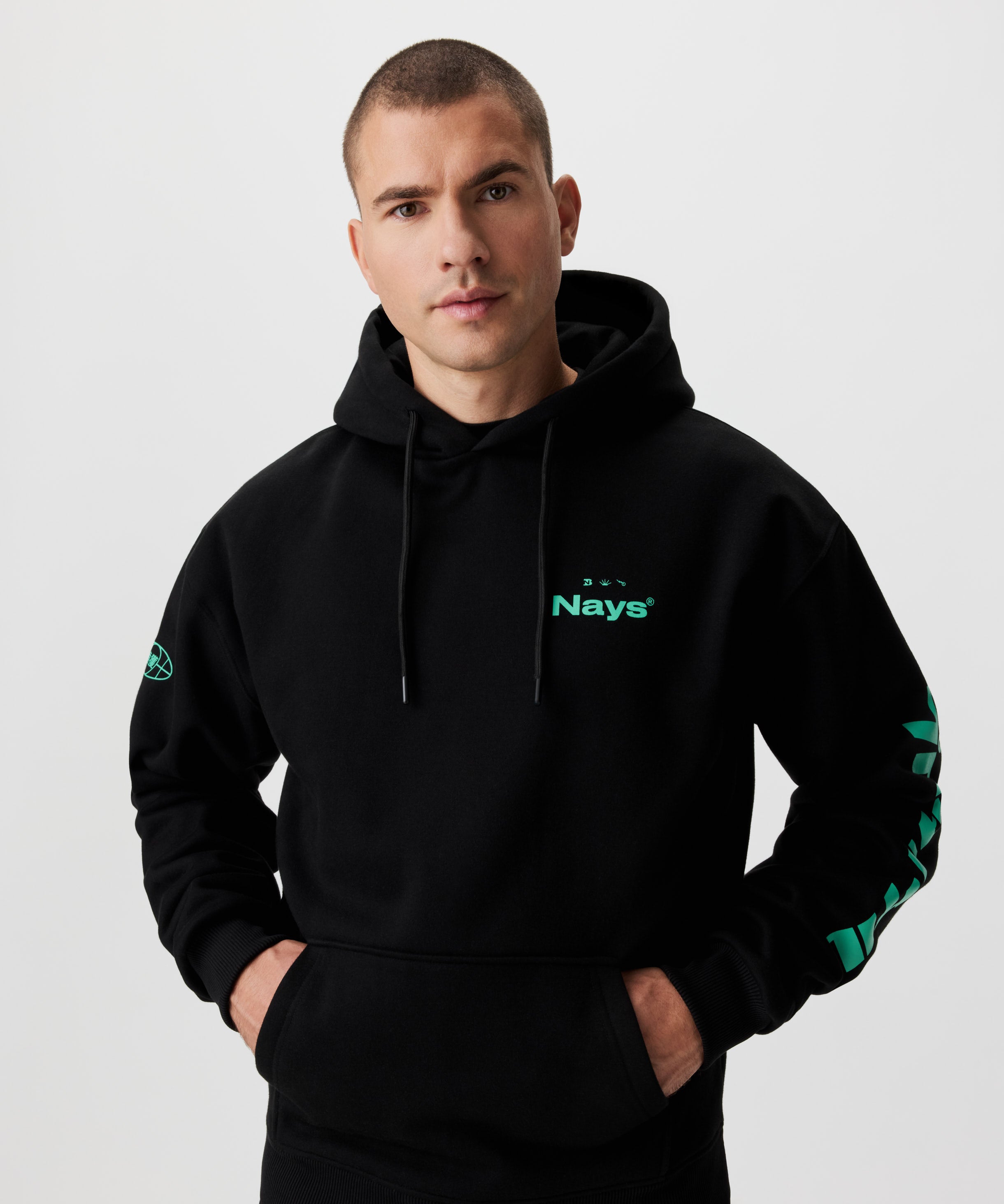 Vorderansicht Mann im schwarzen Kapuzen-Sweatshirt mit grünen Prints auf der Brust und beiden Ärmeln.