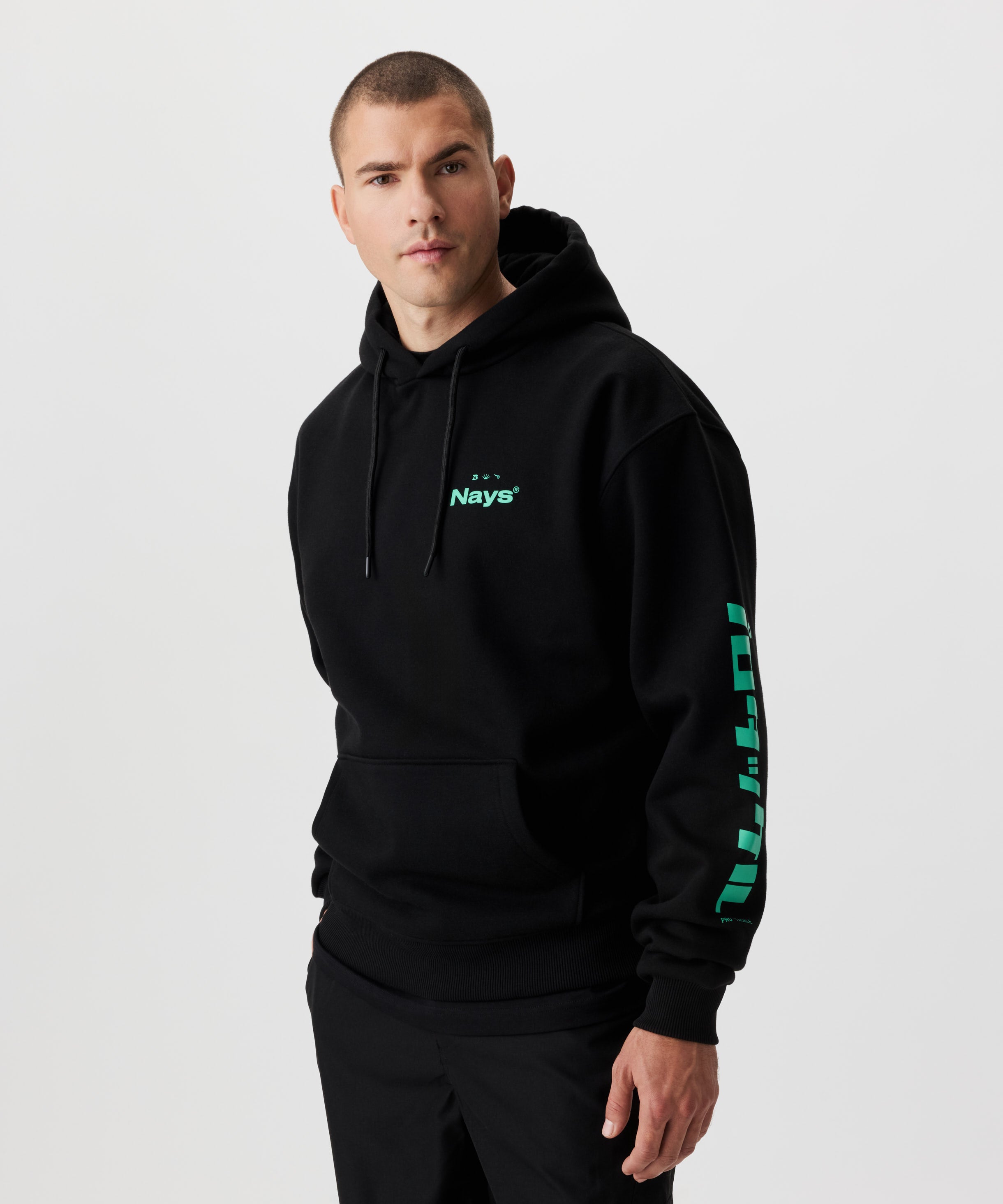 Vorderansicht Mann im schwarzen Kapuzen-Sweatshirt mit grünen Prints auf der Brust und beiden Ärmeln.