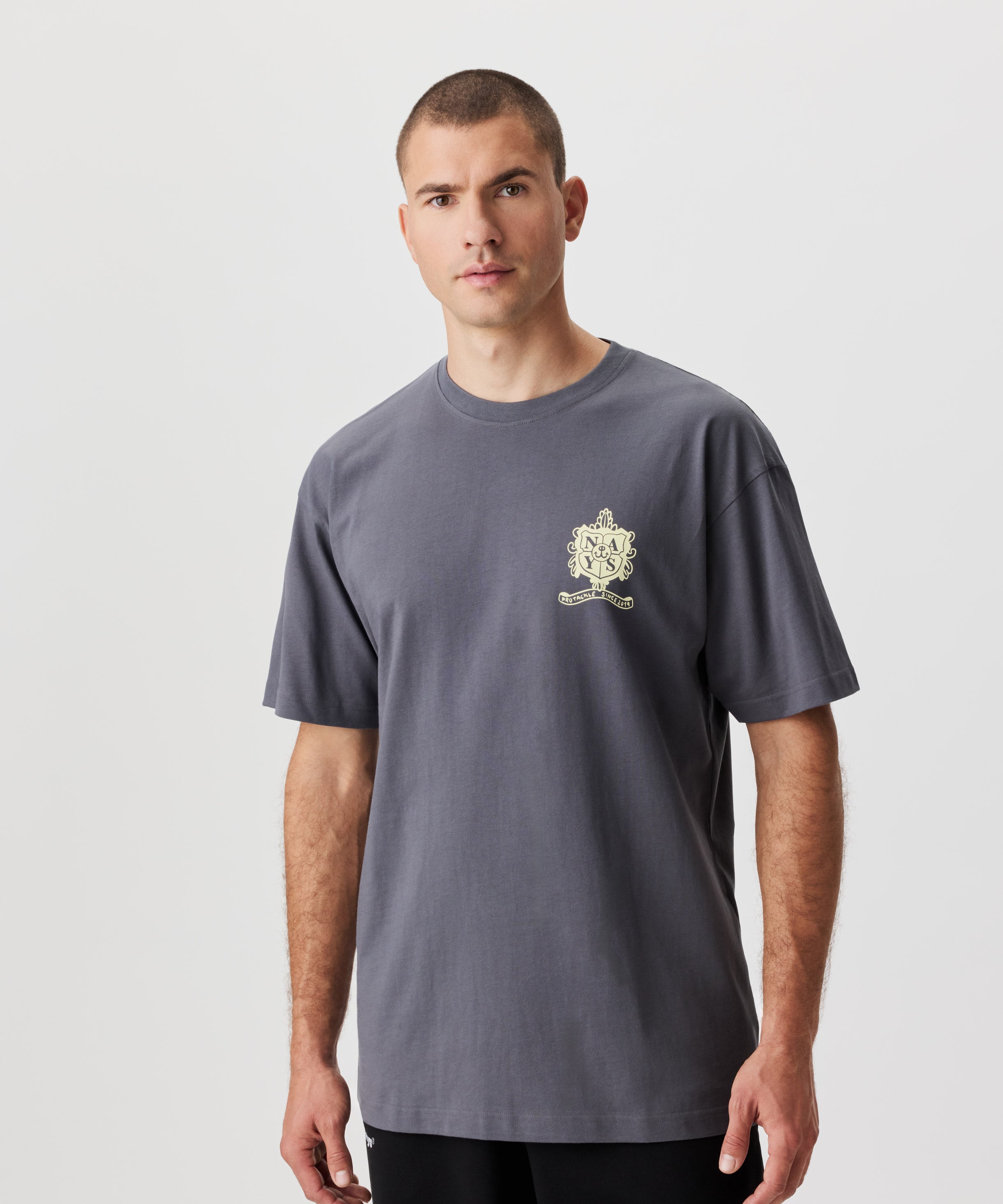 Frontale Ansicht Mann im grauen T-Shirt. Das T-Shirt hat einen gelben Druck auf der linken Brust.