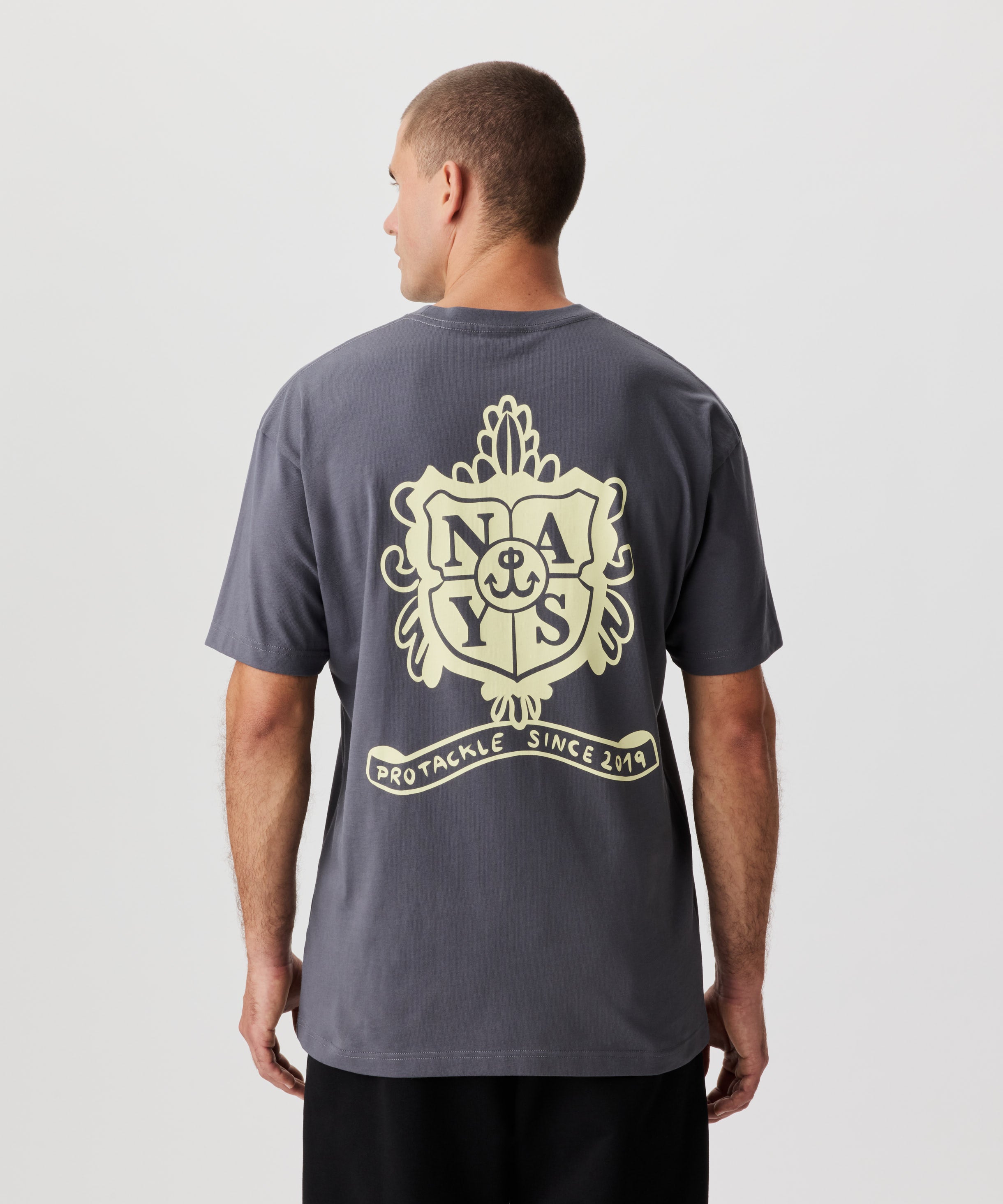 Rückansicht Mann im grauen T-Shirt und schwarzer Hose. Das T-Shirt verfügt über einen grßen, gelben Druck auf dem Rücken.