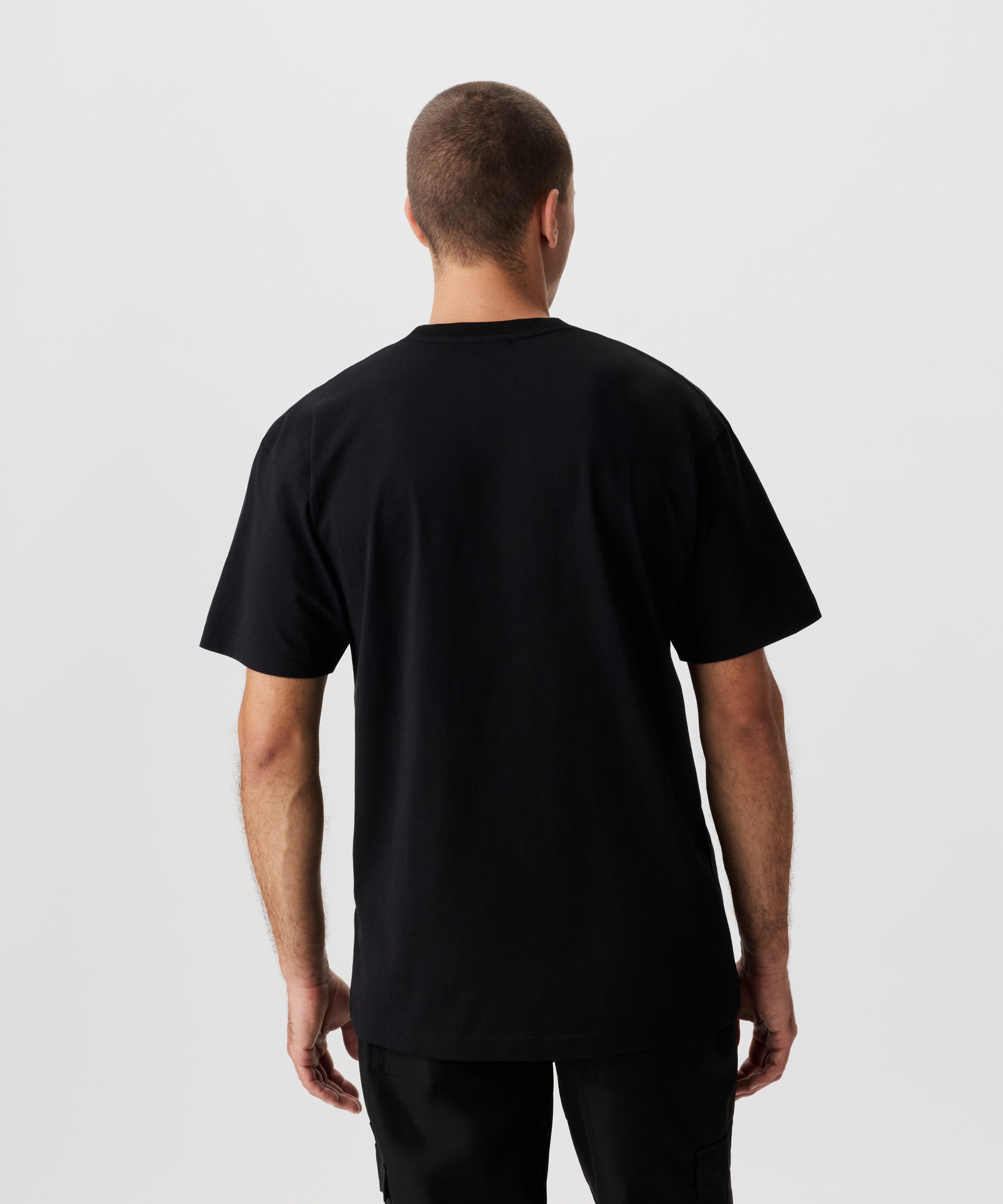 Rückansicht Mann im schwarzen T-Shirt und schwarzer Hose.