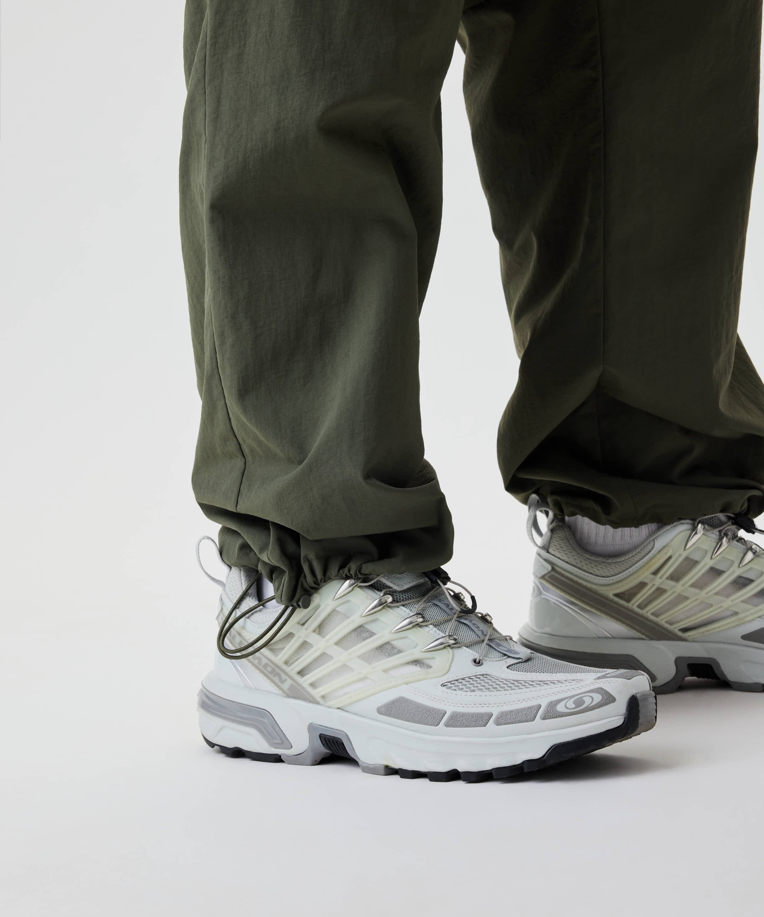 Nahaufnahme von Beinen in Nays Lightweight Zip Off Pants mit Bündchen, kombiniert mit klobigen Trail-Sneakern. Ideal wandelbar für variable Bedingungen und Outdoor-Aktivitäten.