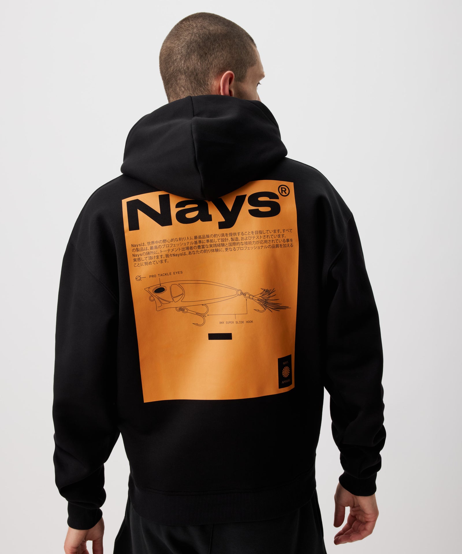 Ein schwarzer Hoodie in Rückenansicht getragen von einem Mann, mit einem großflächigen eckigem Print in leuchtendem Orange. Der Print mit eingelassenem Nays Schriftzug zeigt eine gezeichnete Ansicht eines Köders. 