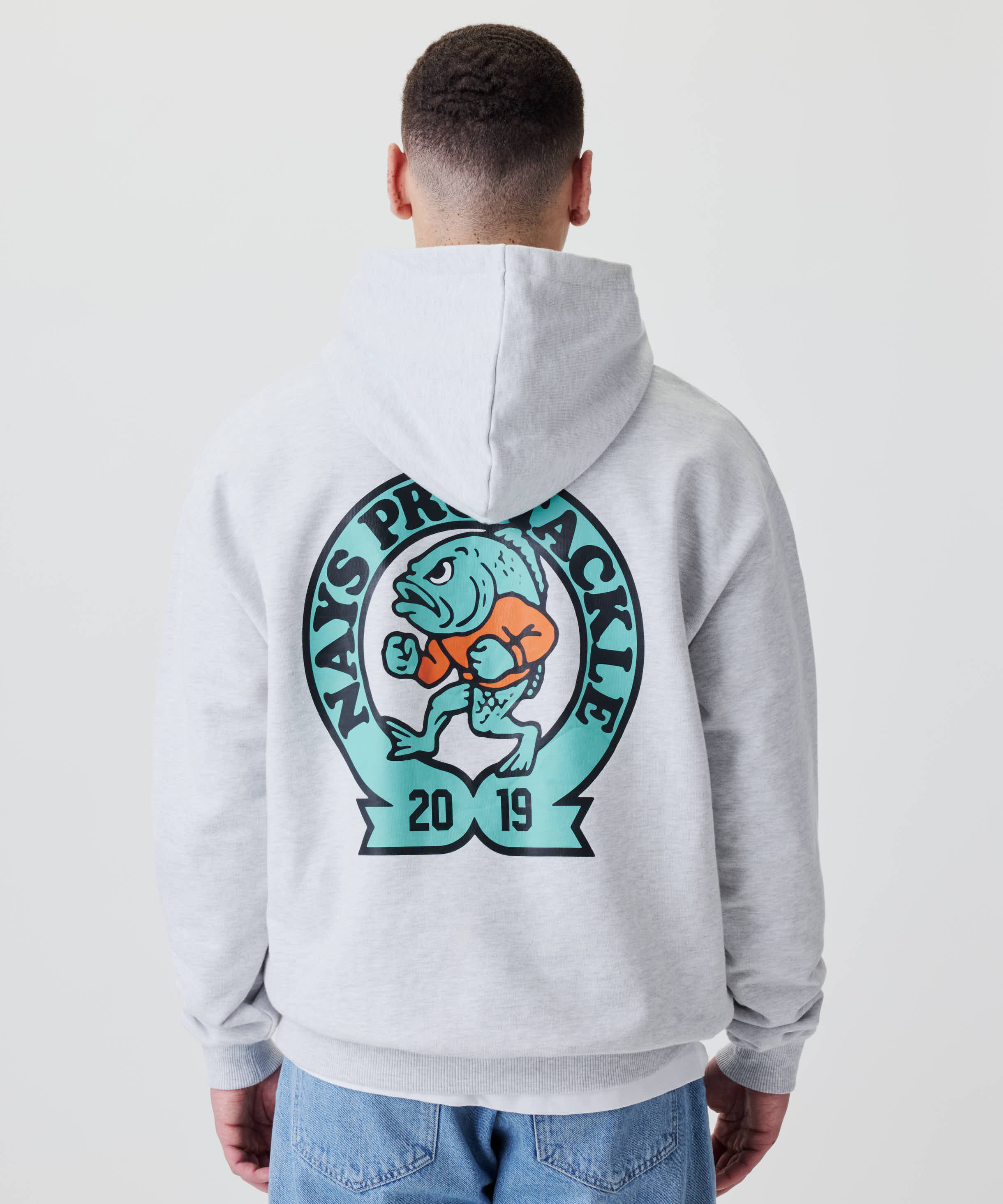 Person von hinten in Nays College Print Hoodie mit großem Logo: cartoonischer Fisch und NAYS PRO TACKLE-Schriftzug auf Rücken. Lässiger, moderner Look.