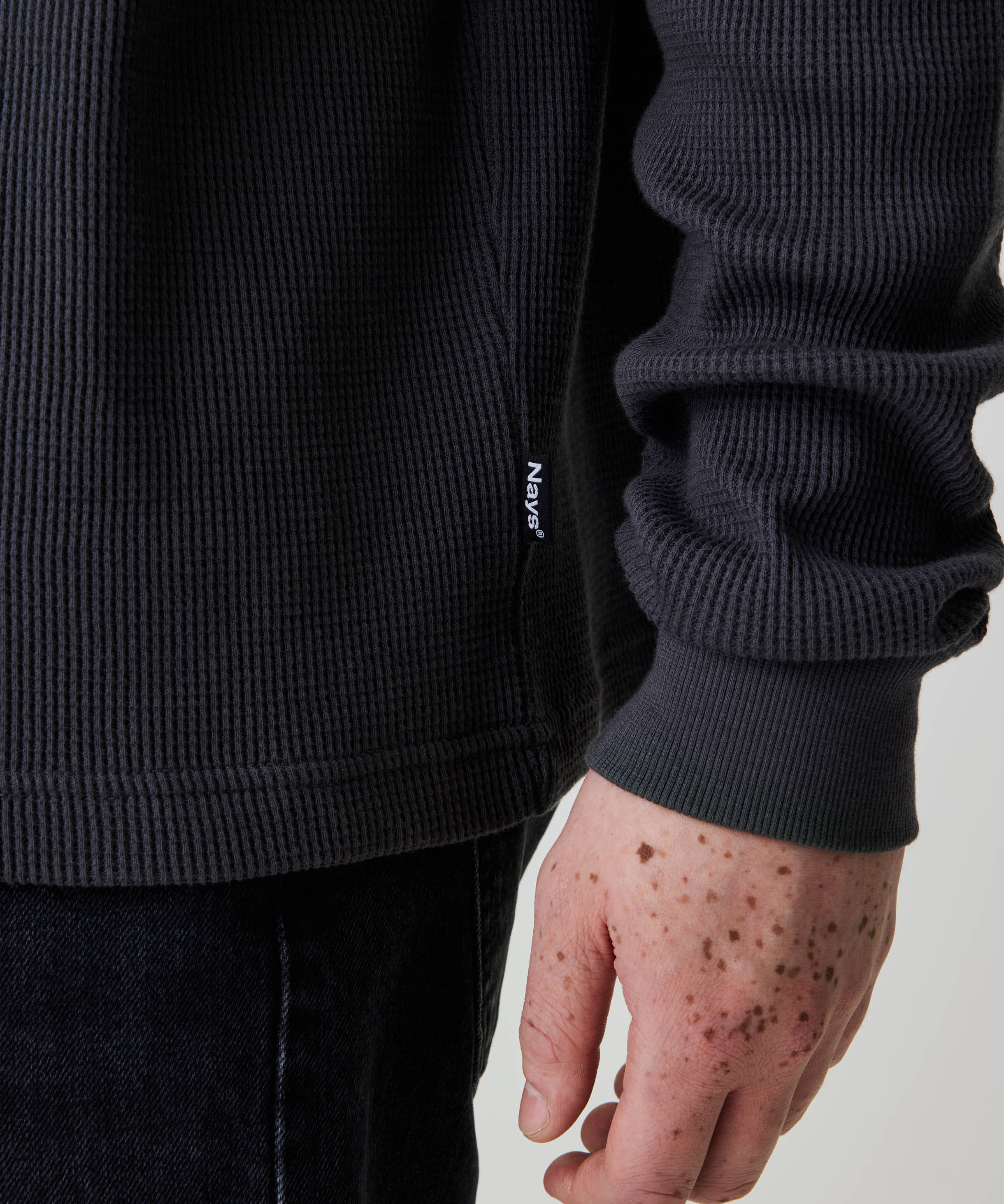 Person trägt das Nays Classic Waffle Longsleeve in Anthrazit, das durch sein strukturiertes Material und dezentes Nays®-Label an der Seitennaht besticht.