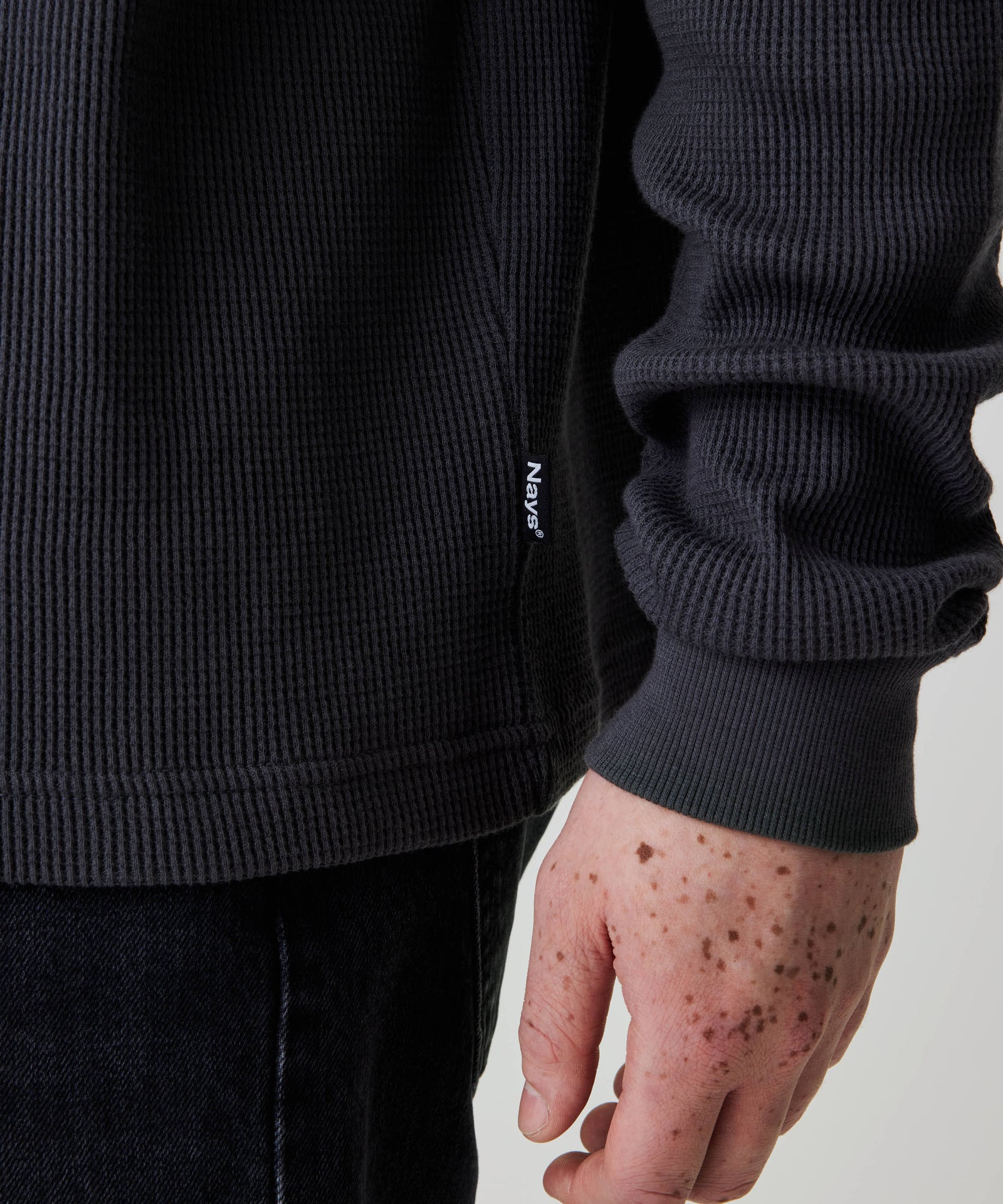 Person trägt das Nays Classic Waffle Longsleeve in Anthrazit, das durch sein strukturiertes Material und dezentes Nays®-Label an der Seitennaht besticht.