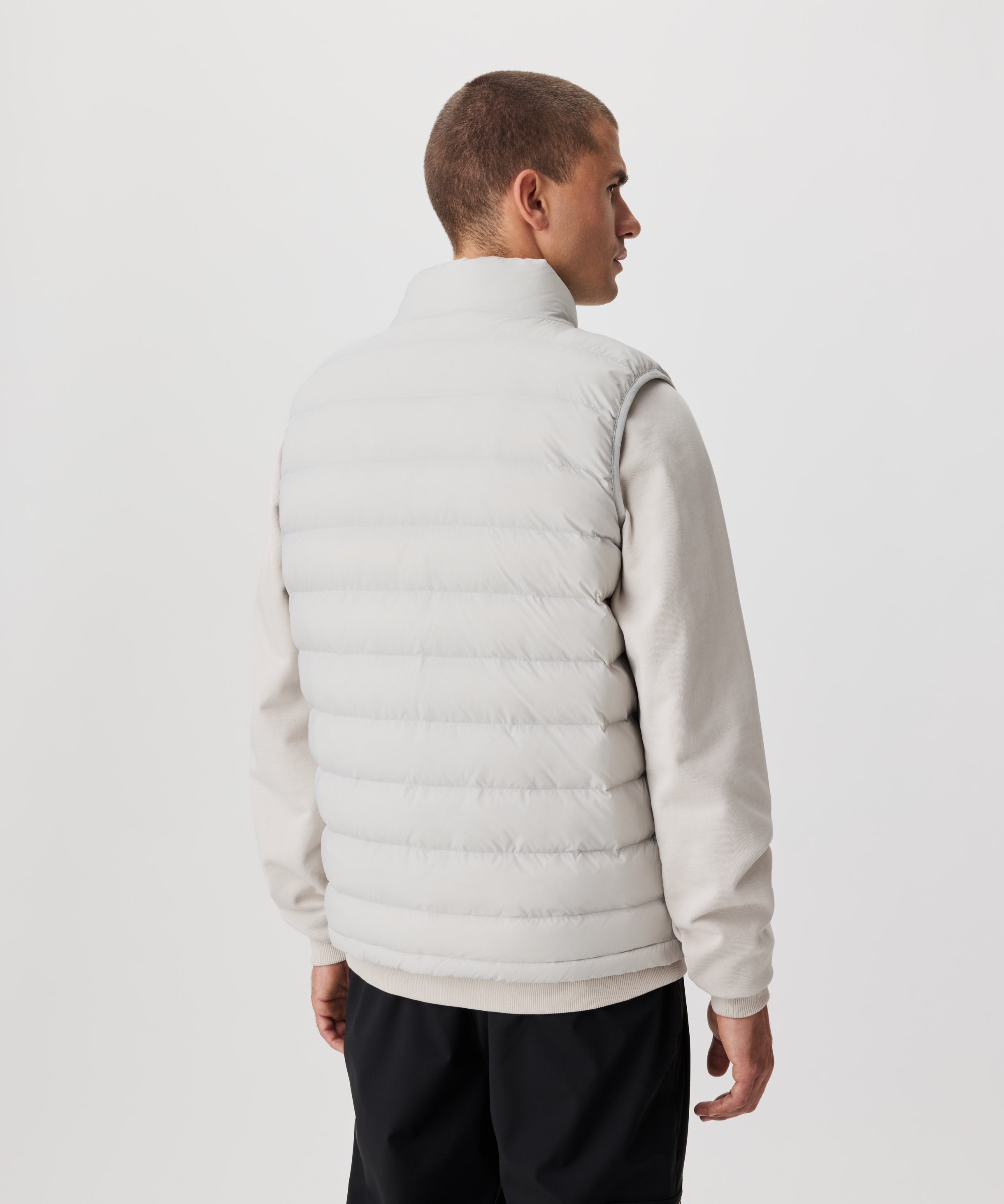 Rückansicht Mann in hell-grauer Weste und schwarzer Hose.