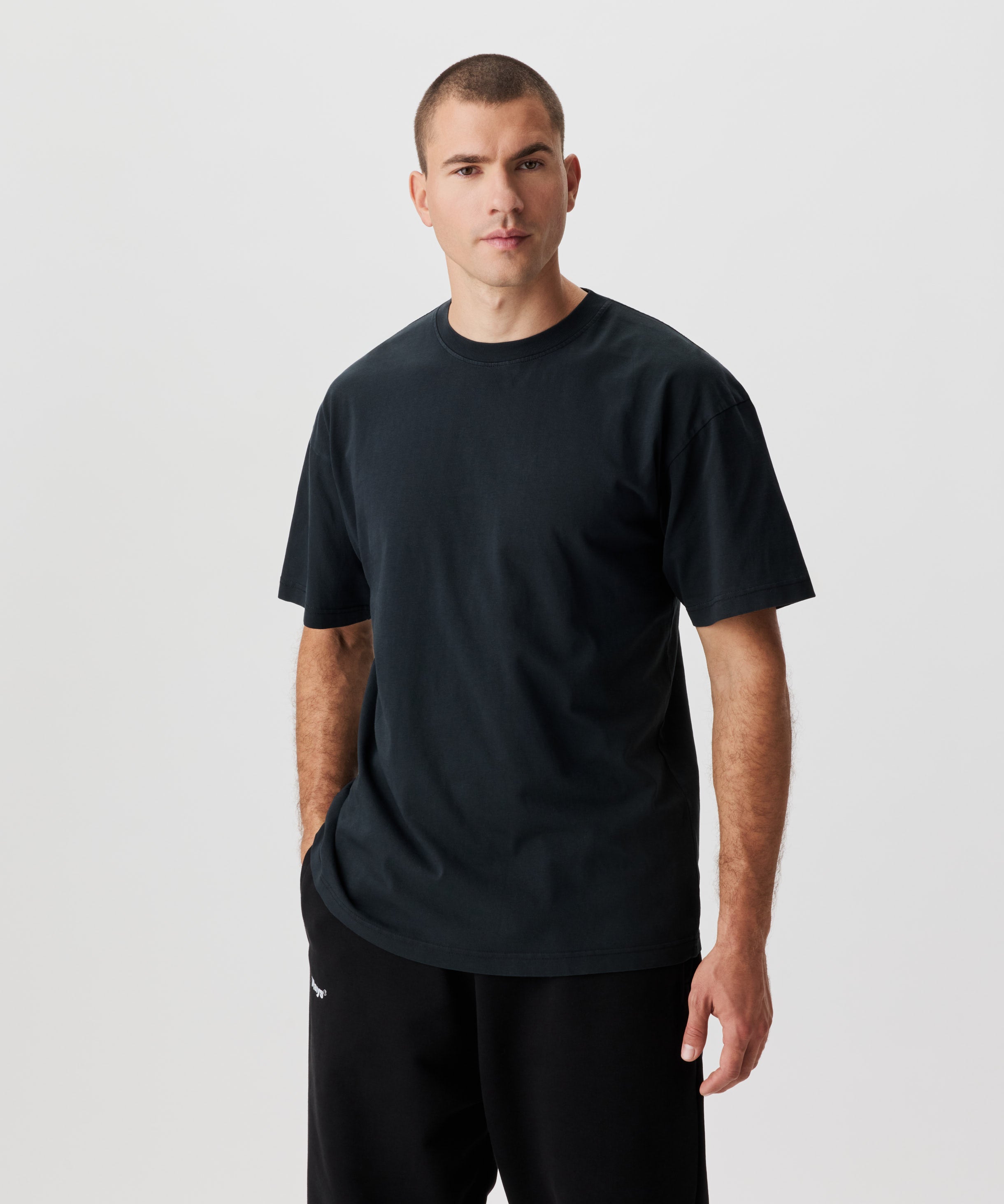 Frontale Ansicht  Mann mit anthrazitfarbenem T-Shirt und schwarzer Hose.