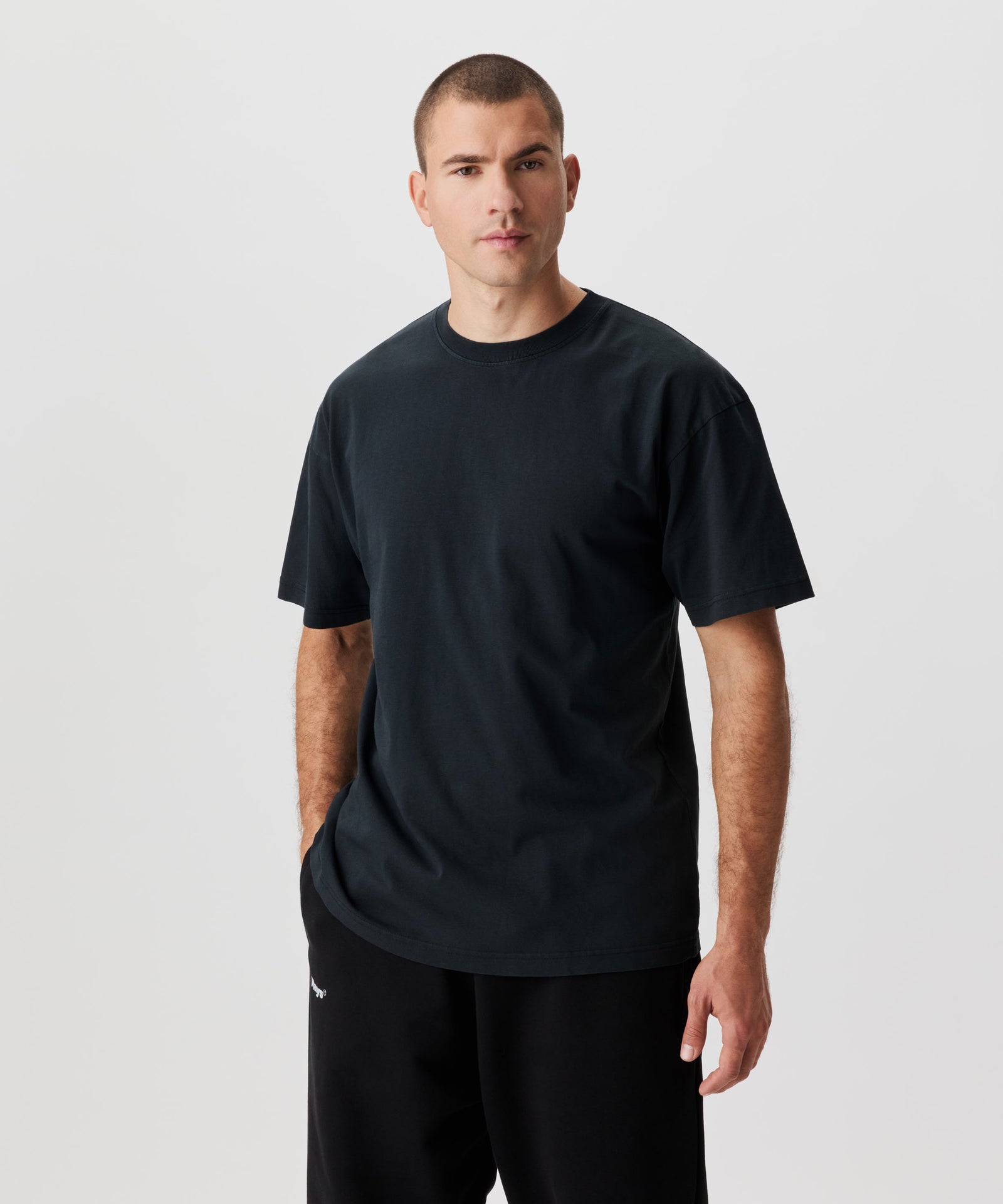 Frontale Ansicht  Mann mit anthrazitfarbenem T-Shirt und schwarzer Hose.