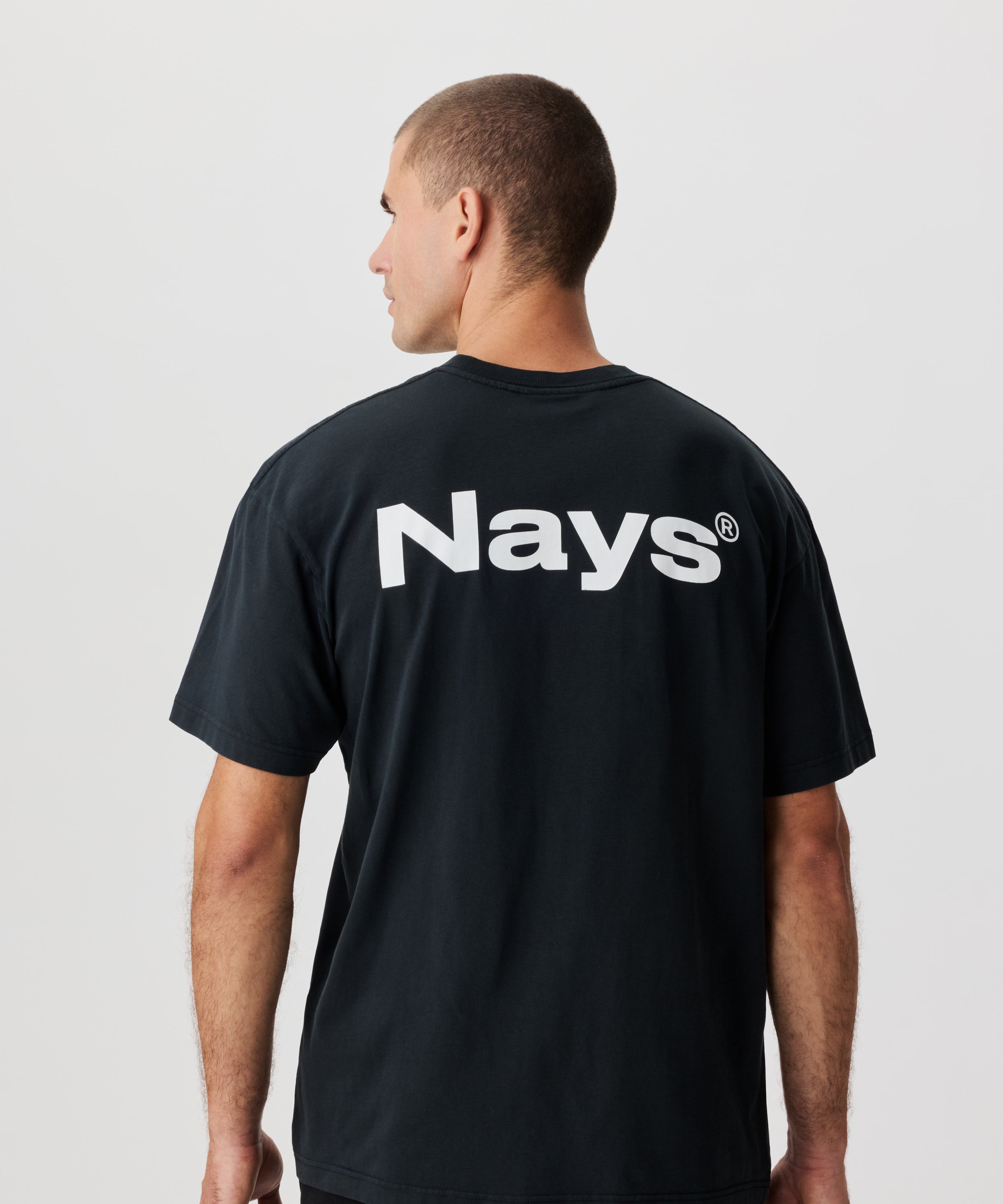 Rückenansicht Mann mit anthrazitfarbenem T-Shirt und großem NAYS-Logo-Aufdruck.