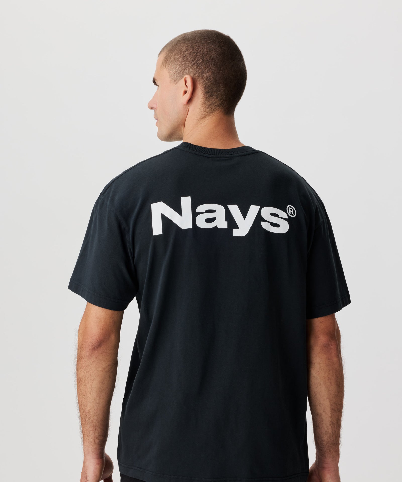 Rückenansicht Mann mit anthrazitfarbenem T-Shirt und großem NAYS-Logo-Aufdruck.
