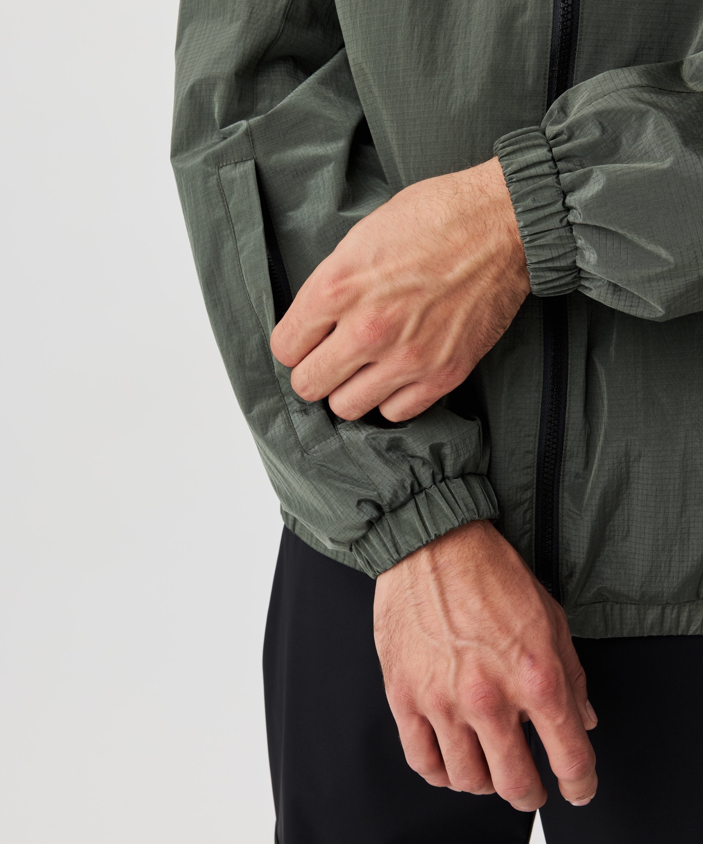 Mann in grüner Blouson Jacke in der Detail-Ansicht. Die Jacke verfügt über eine kleine Tasche im rechten Ärmel.